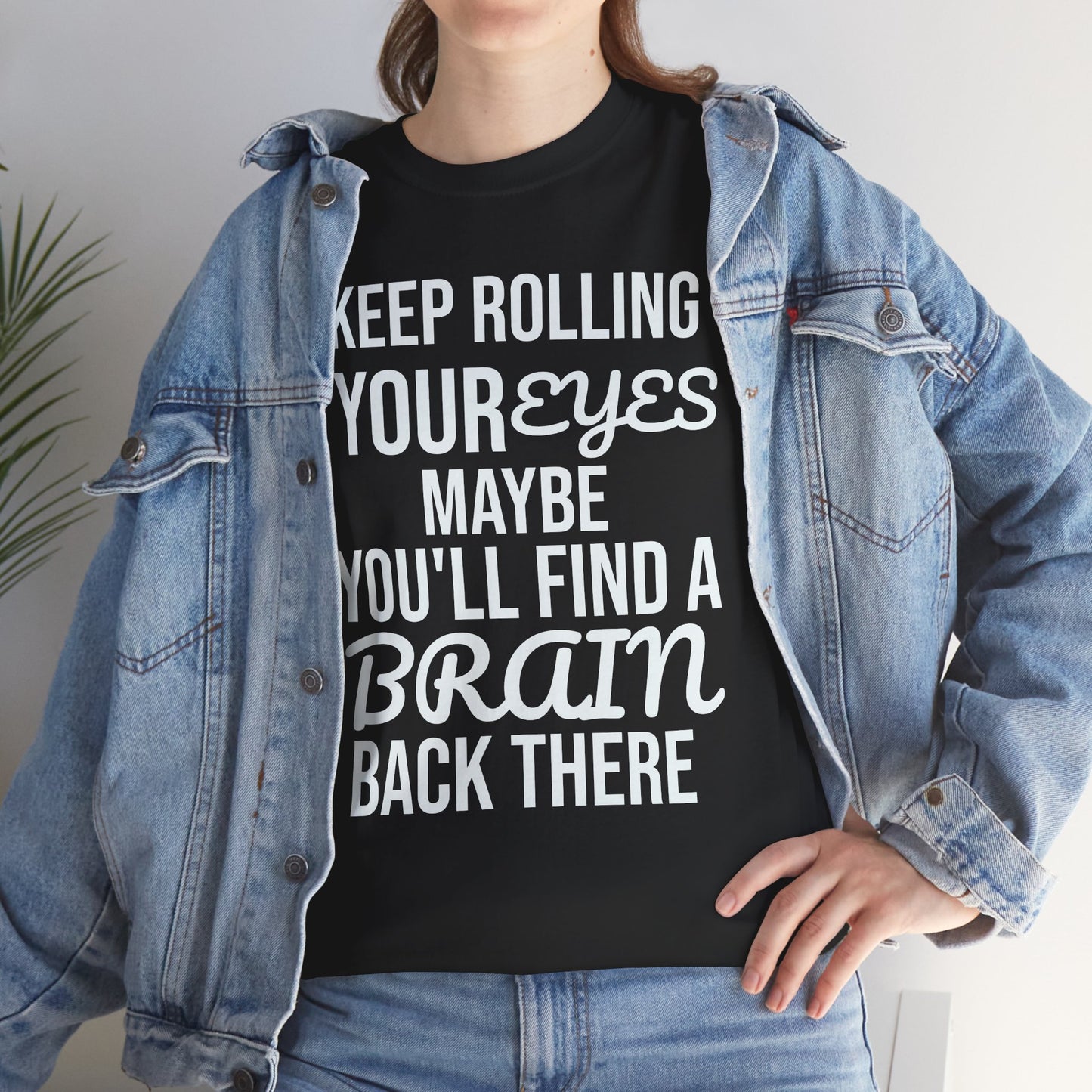 Person wearing a black t-shirt with humorous text 'KEEP ROLLING YOUR EYES MAYBE YOU'LL FIND A BRAIN BACK THERE' and a denim jacket.