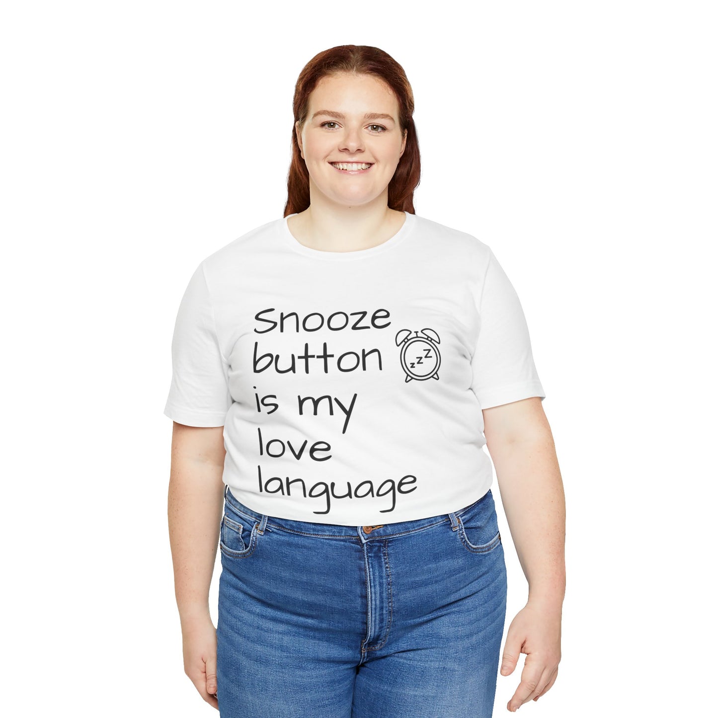 Person wearing a white t-shirt with text 'Snooze button is my love language' and blue jeans on a white background