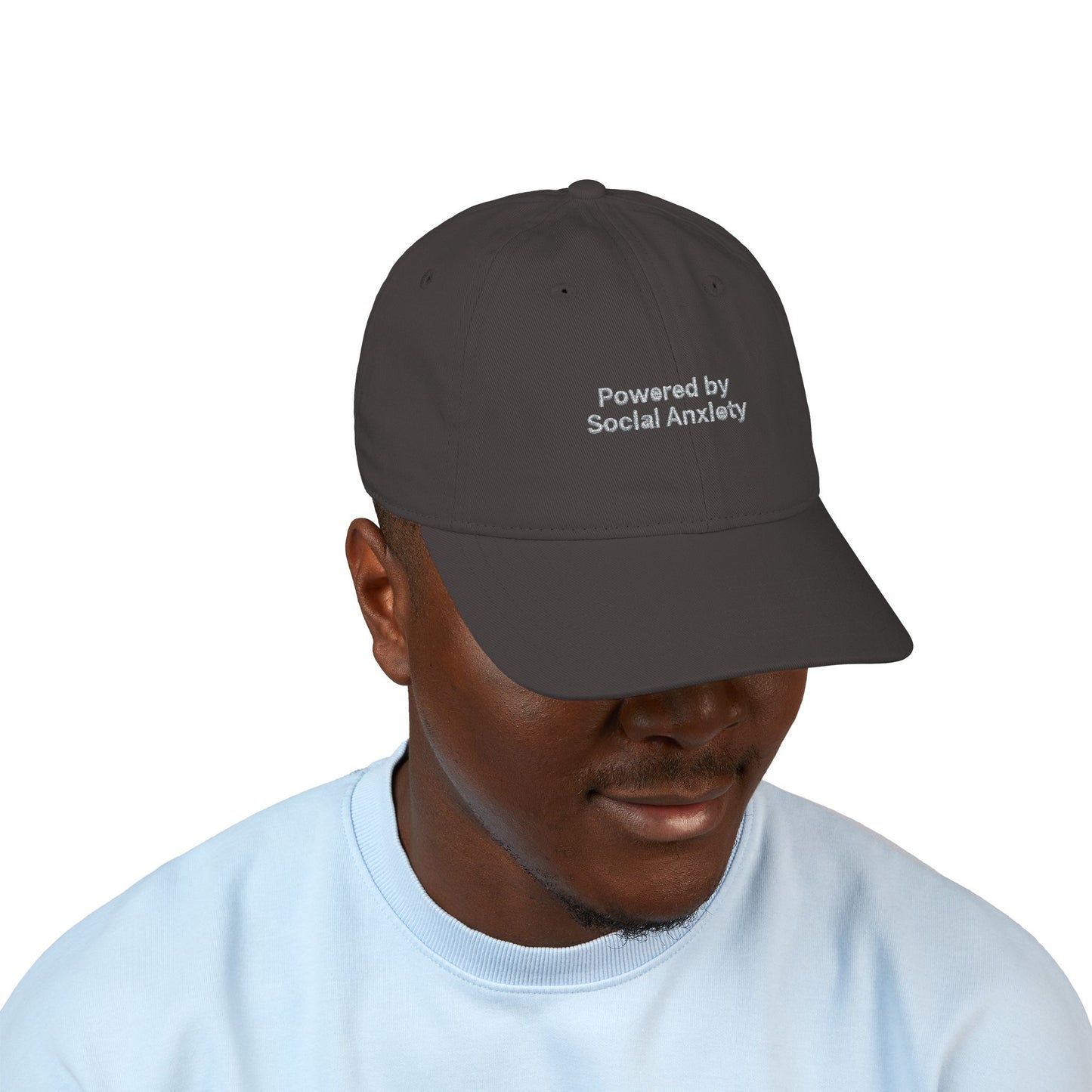 Person wearing a dark gray cap with 'Powered by Social Anxiety' text on a white background