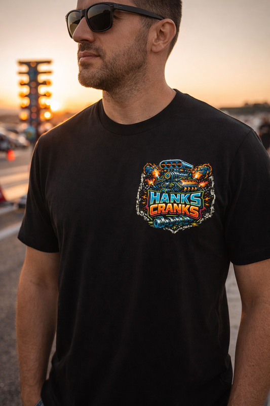 Man wearing black Hanks Cranks drag racing t-shirt with small front chest logo at the drag strip during sunset.