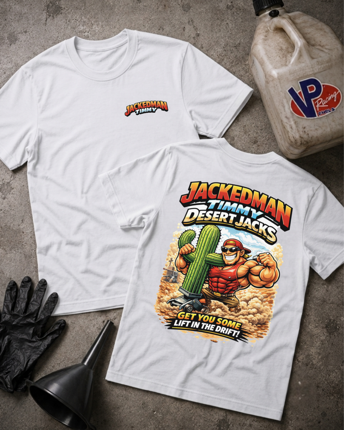 Two white graphic T-shirts laid flat on a gray concrete surface, with a black oil bottle, black gloves, and a funnel nearby. The front shirt shows a small red and yellow chest logo, and the back shirt shows a large colorful graphic of a muscular man holding a cactus with the text 'JACKEDMAN TIMMy DESERT JACKS' and 'GET YOU SOME LIFT IN THE DRIFT!'.