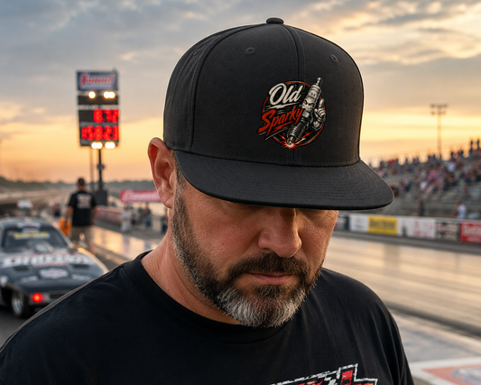 Man wearing a black cap with a Old Sparky logo at a race track during sunset.