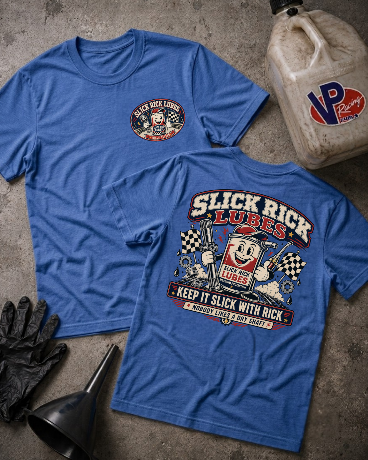 Two blue short-sleeve graphic T-shirts laid flat on a textured gray surface, with a vintage-style 'Slick Rick Lubes' chest logo on the front view and a large back graphic. Black gloves and a black funnel are placed beside them, along with a dirty plastic jugs labeled VP Racing.