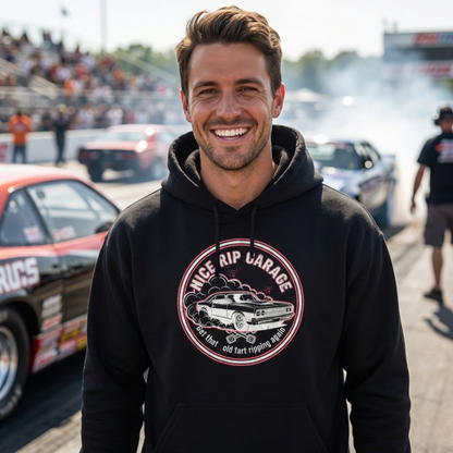 Man wearing a black hoodie with a graphic design and 'Nice Rip Garage Get that old fart ripping again' text at a race track