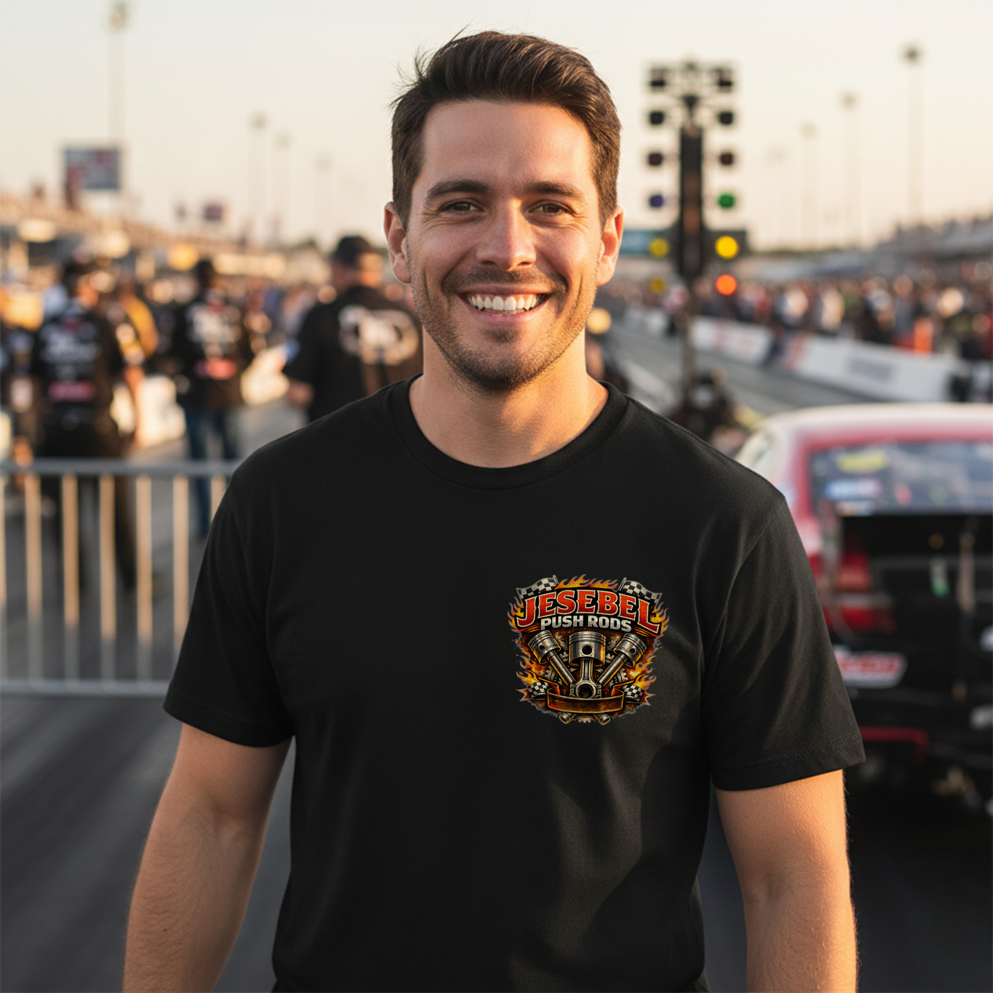 Man wearing a black t-shirt with a colorful 'Jesebel Push Rods' logo at drag race