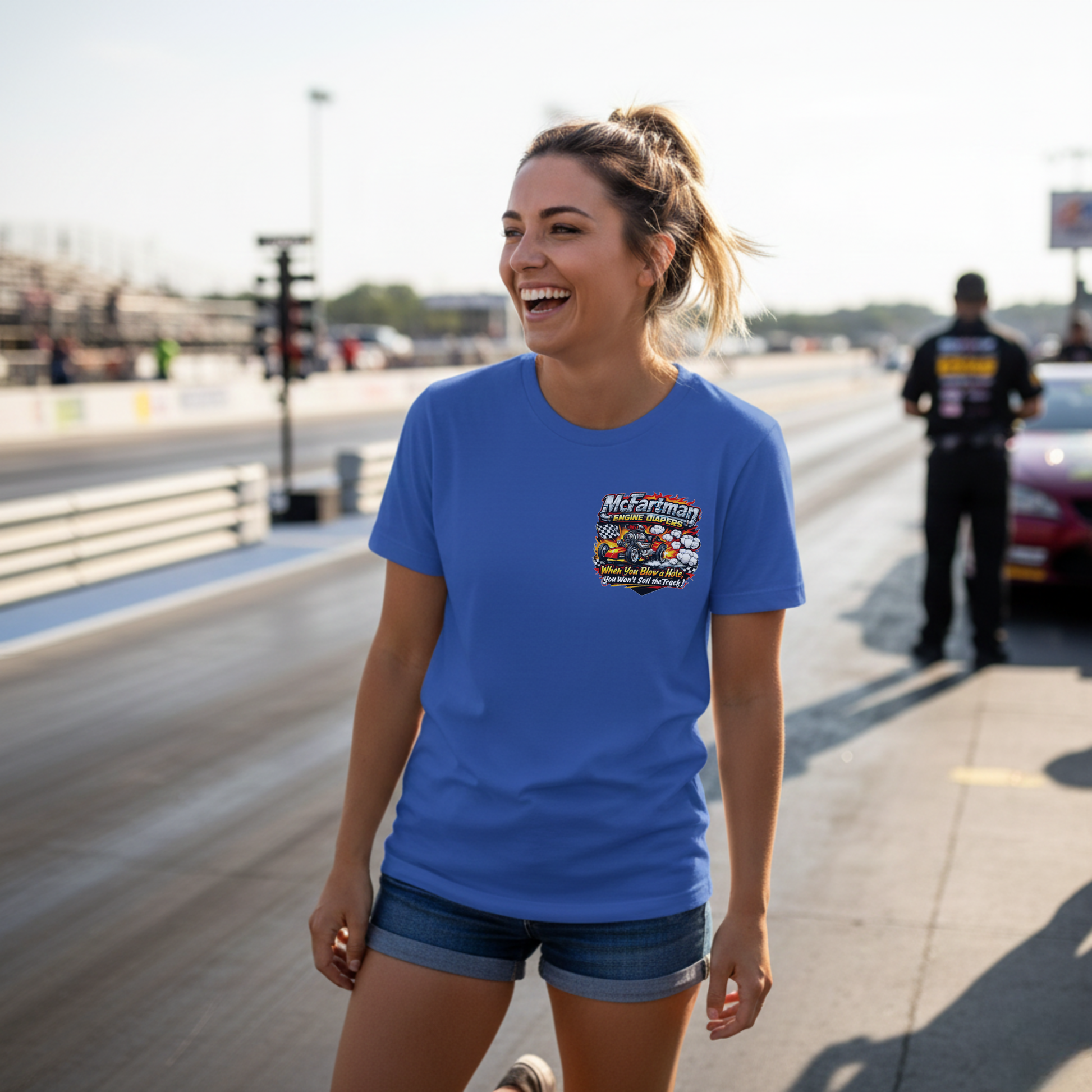 Woman wearing a blue t-shirt with a graphic design 'McFartman Engine Diapers' logo on a race track