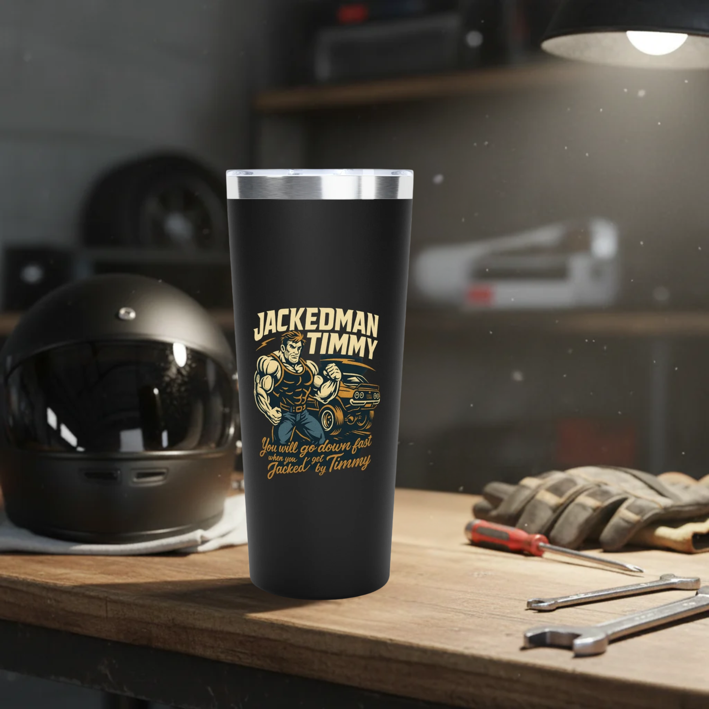 Black tumbler with 'Jackedman Timmy' design on a workbench with tools and a helmet.