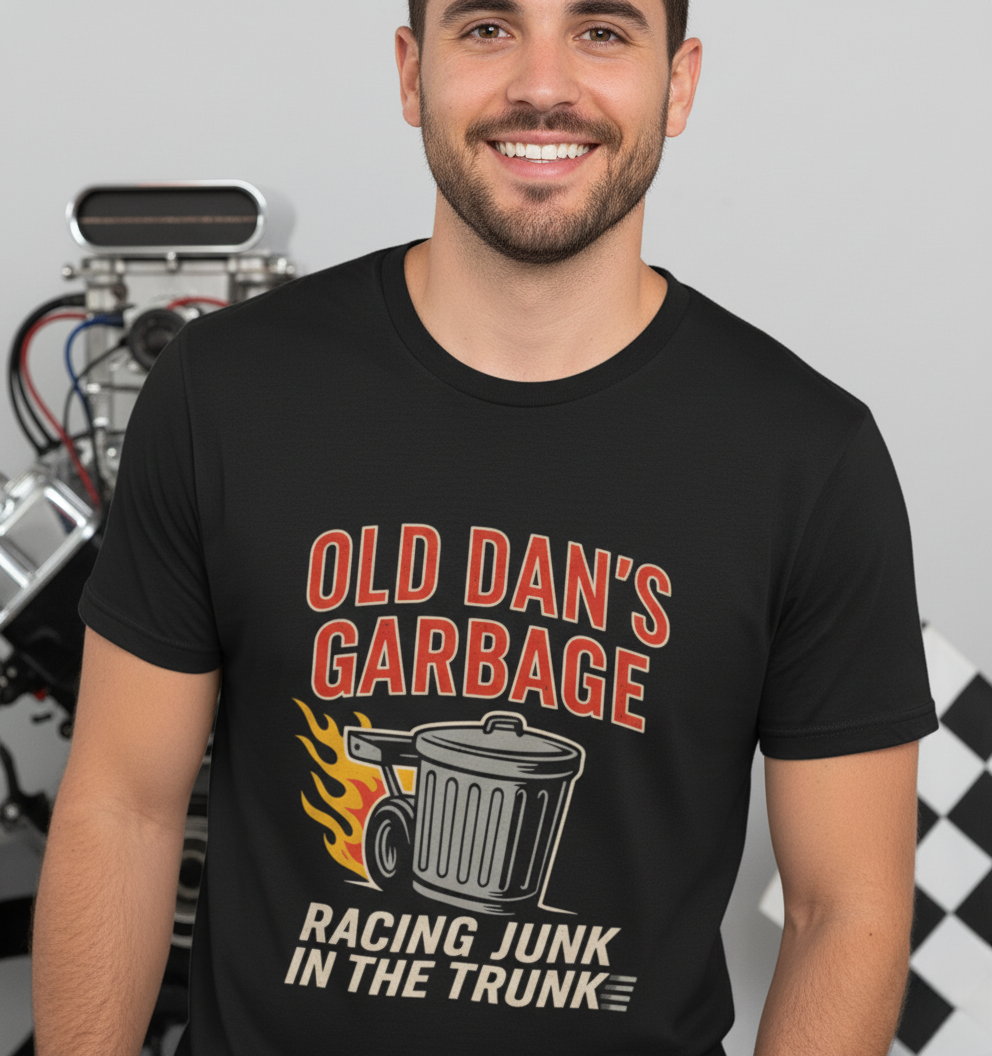 Person wearing a black graphic T‑shirt featuring the bold red and white text “Old Dan’s Garbage” above a flaming garbage can illustration, with the tagline “Racing Junk in the Trunk” below. Funny drag racing parody shirt with retro racing flames, checkered flag background, and humor‑driven hot rod style, perfect for car enthusiasts and gearhead apparel fans.