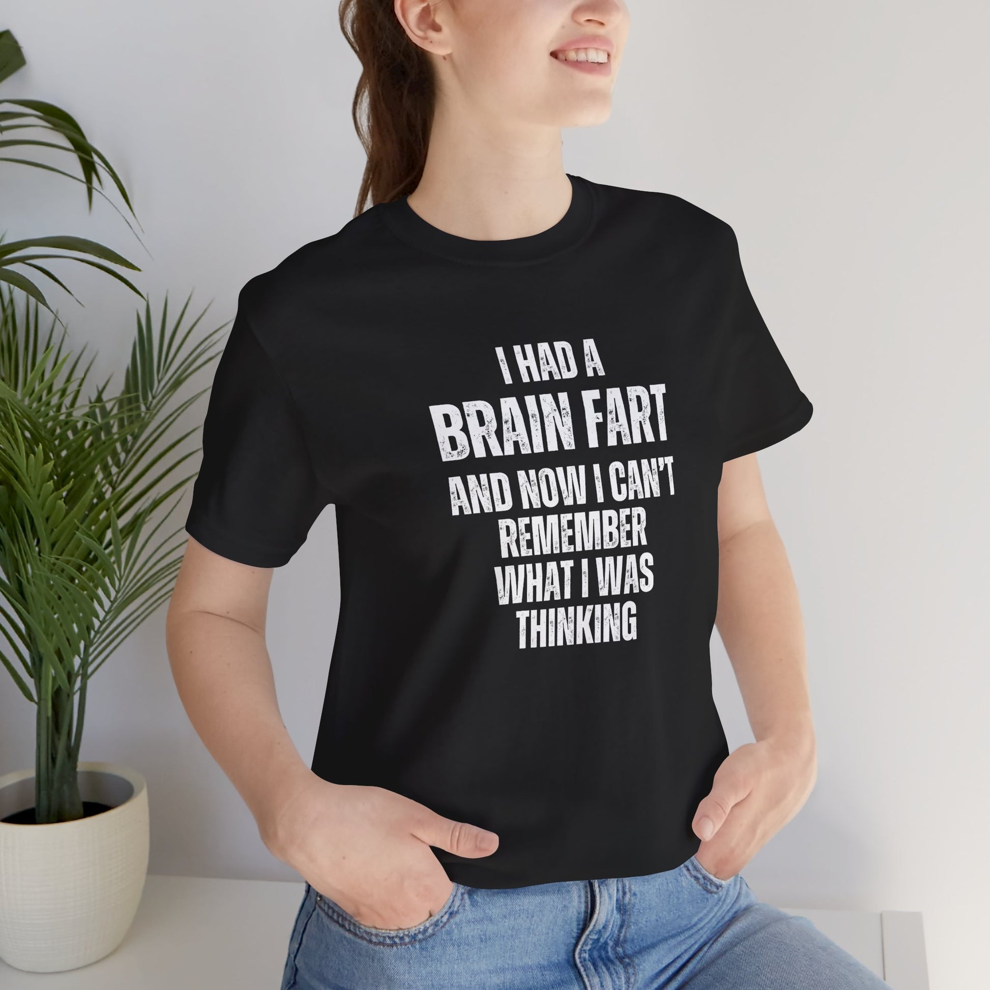 Person wearing a black t-shirt with humorous text 'I had a brain fart and now I can't remember what I was thinking' in a casual setting