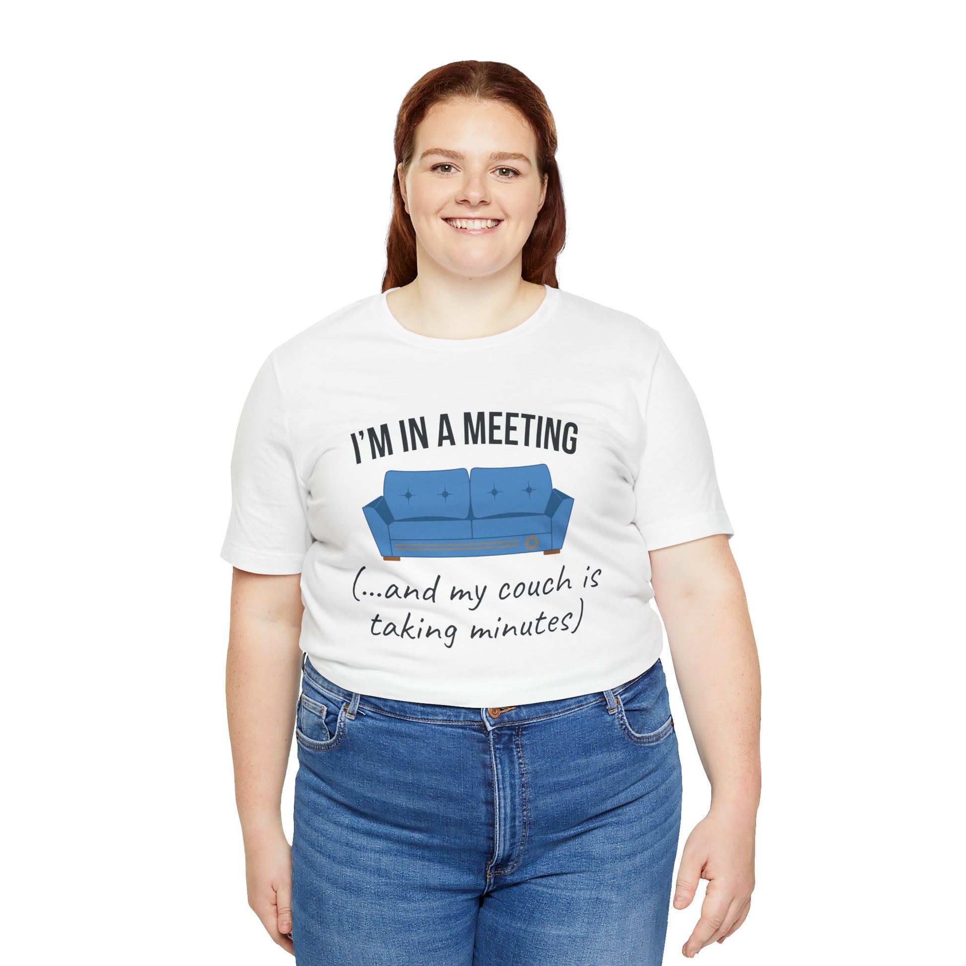 Person wearing a white t-shirt with a graphic and text 'I'm in a meeting (...and my couch is taking minutes)', standing against a white background