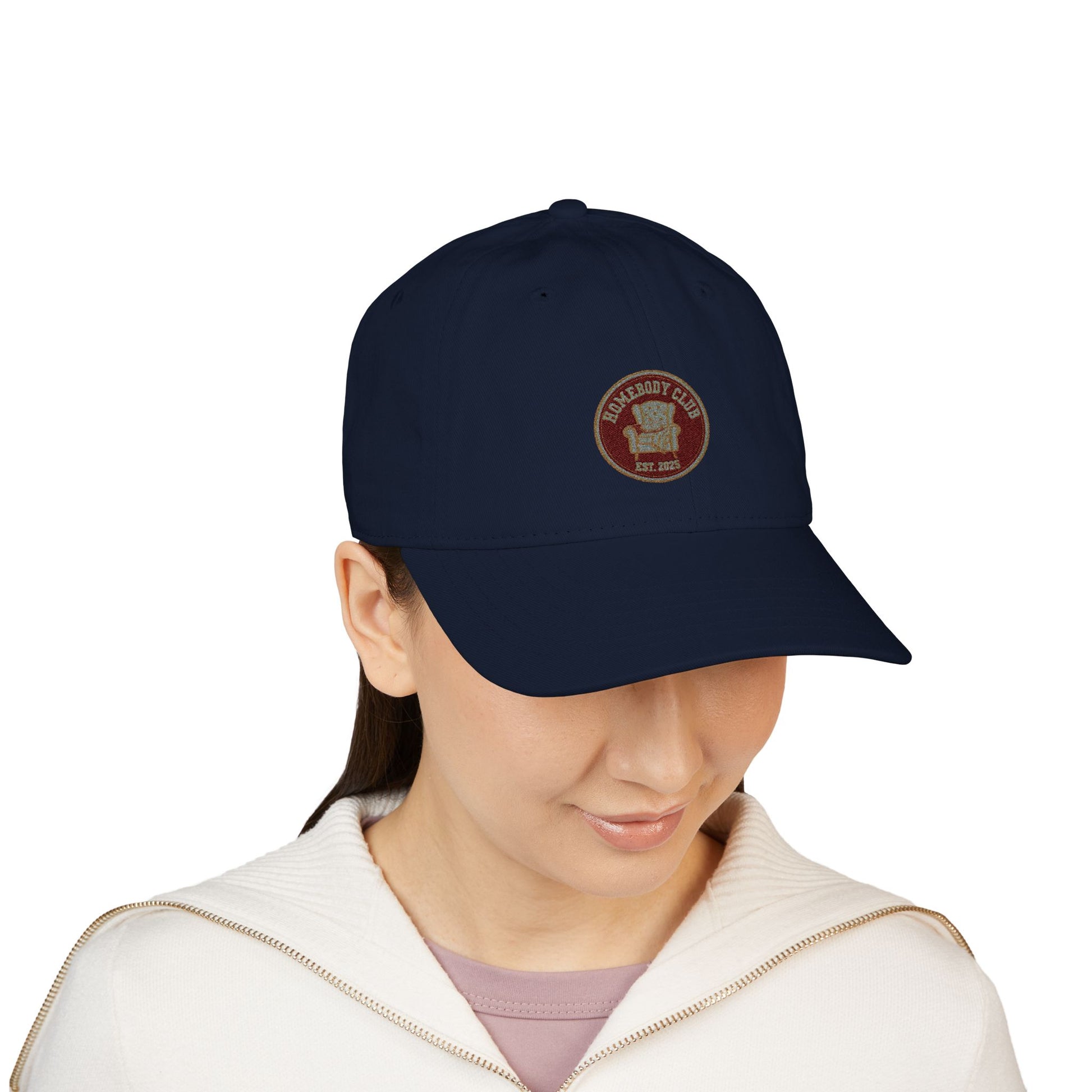 Person wearing a navy blue cap with a logo and text 'Homebody club Est. 2025' on a white background