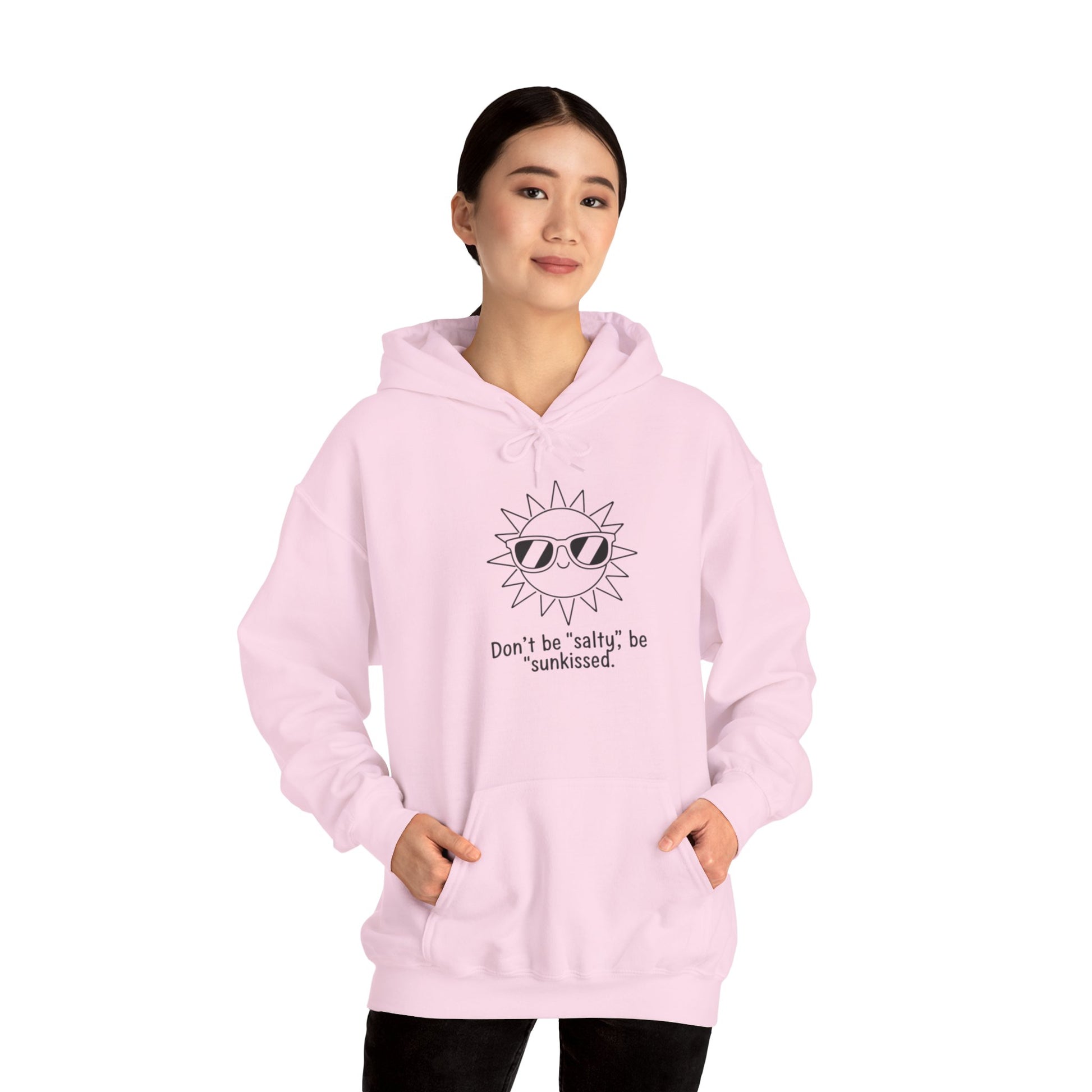 Person wearing a pink hoodie with sunglasses and text 'Don't be salty, be sunkissed' design on a white background