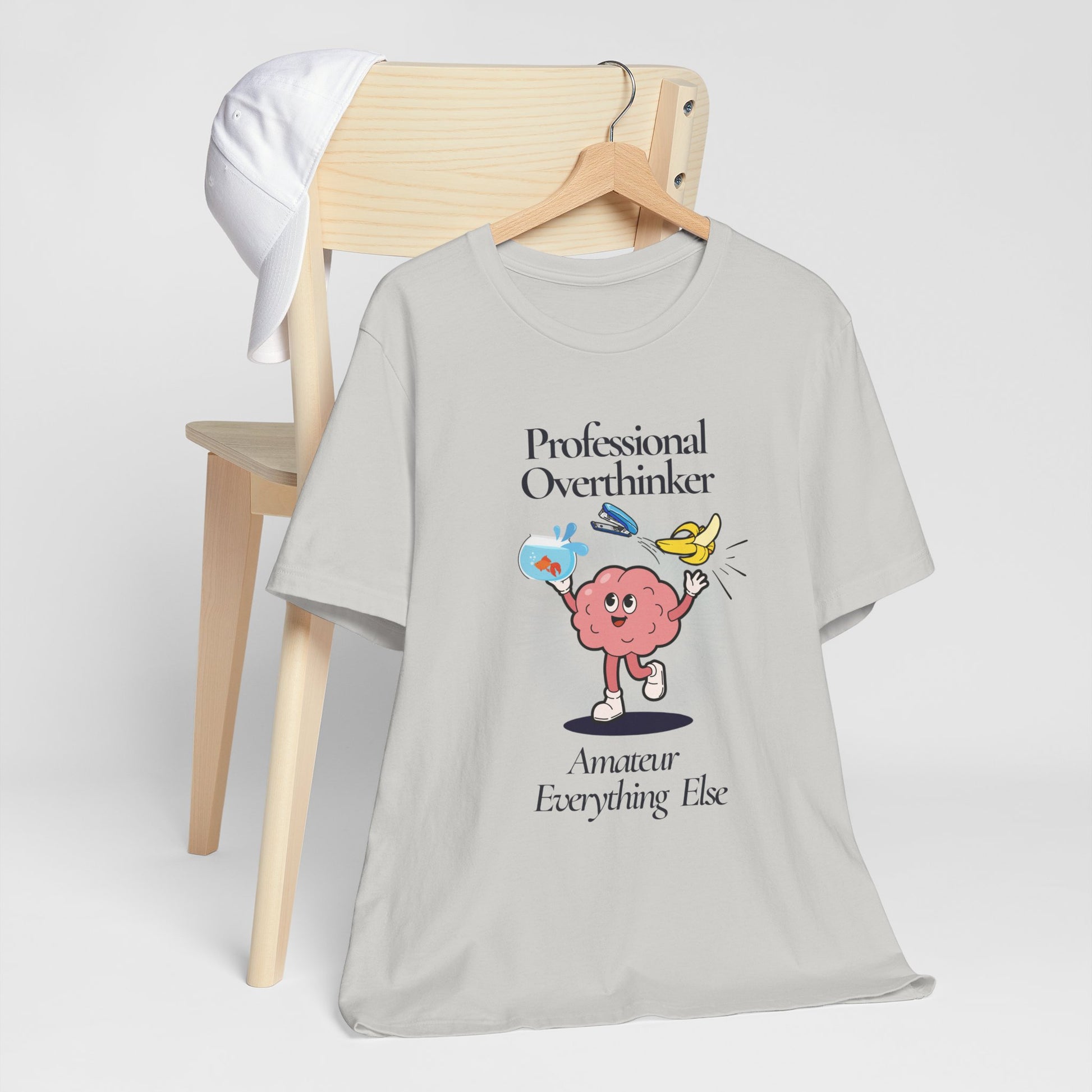 Gray t-shirt with a brain graphic and text 'Professional Overthinker, Amateur Everything Else' on a white background