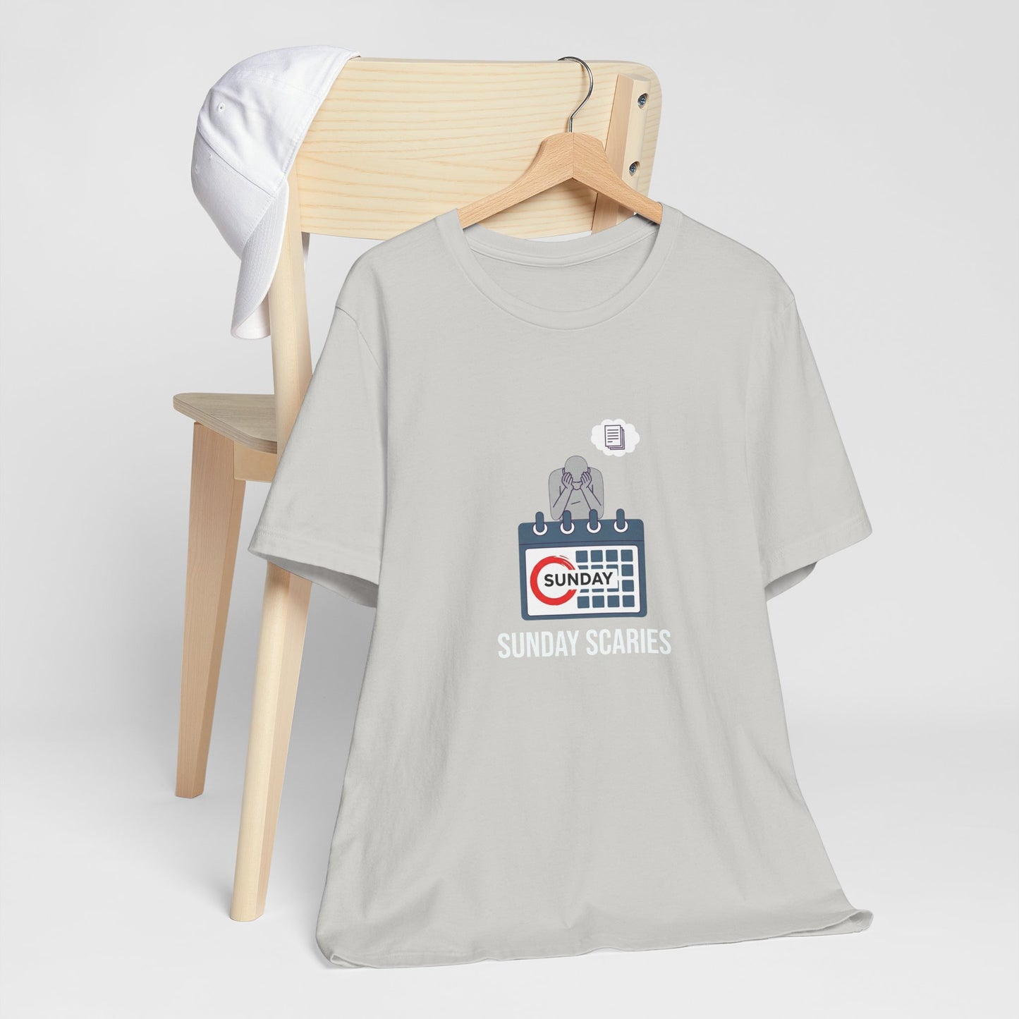 Gray t-shirt with graphic design and text 'Sunday Scaries' on a wooden chair against a white background