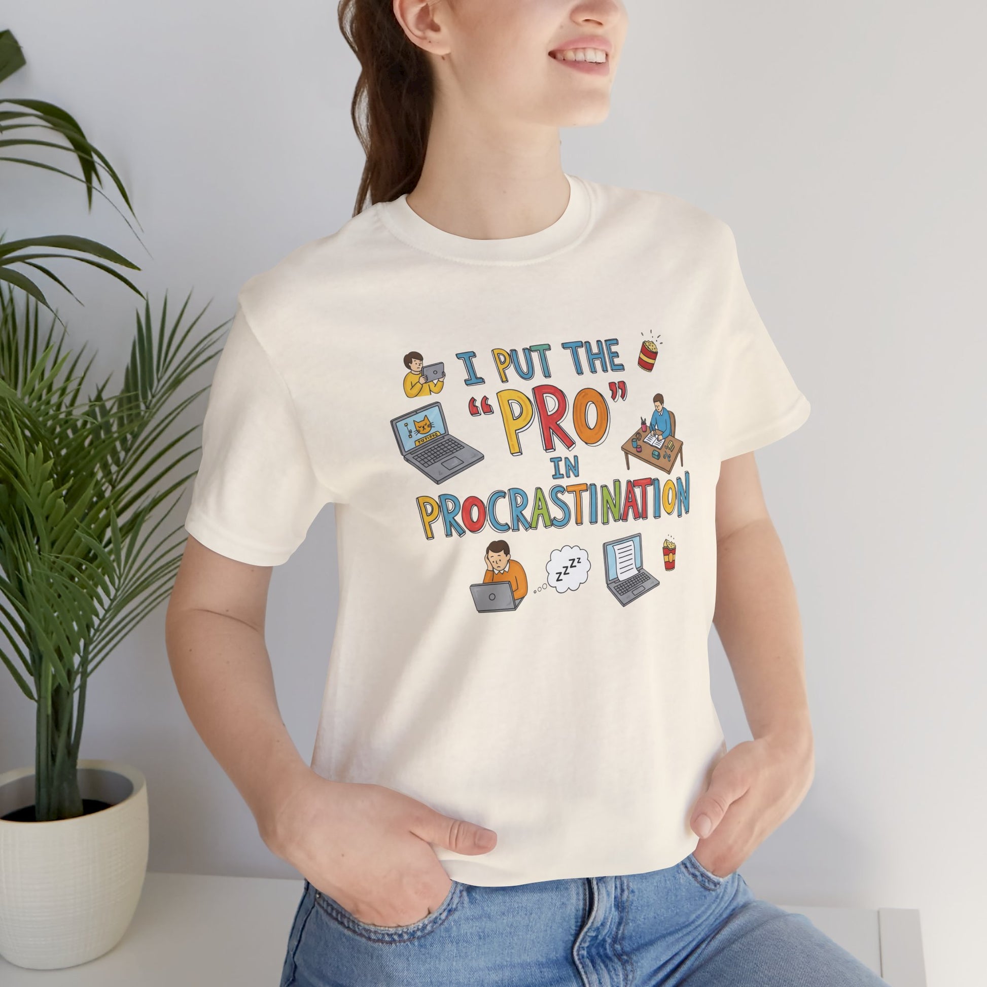 Person wearing a white t-shirt with colorful text and graphics, sitting indoors.