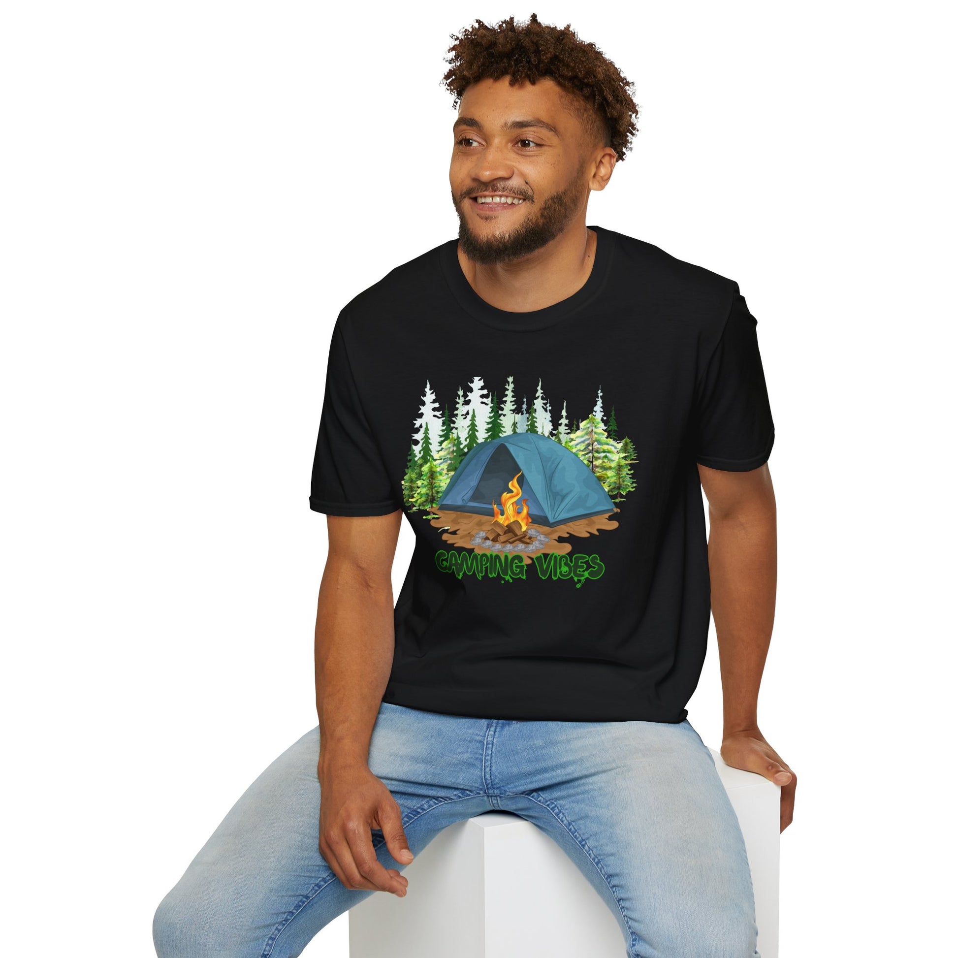 Man wearing a black t-shirt with a camping graphic and text, sitting on a white stool.