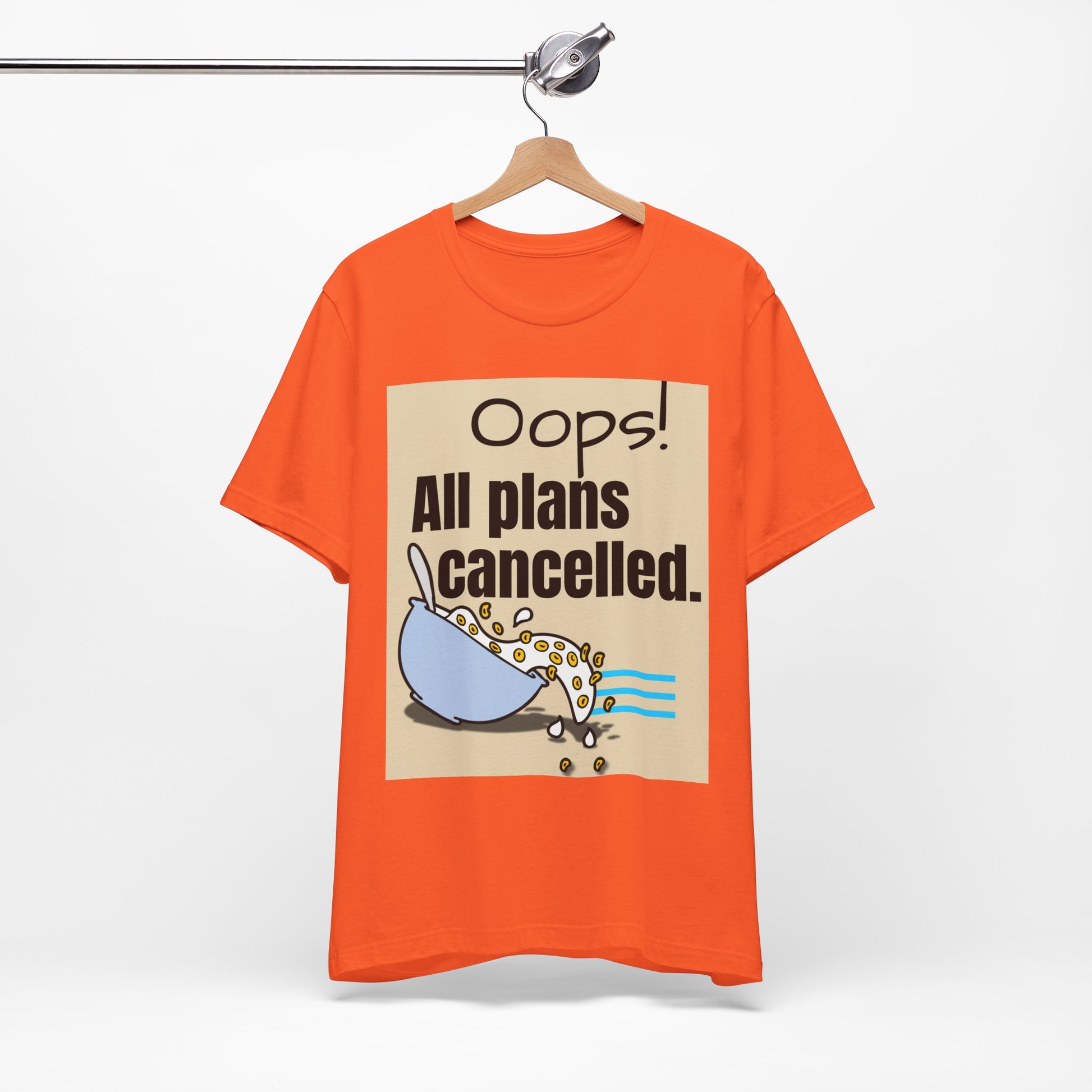 Orange t-shirt with graphic and text 'Oops! All plans cancelled.' on a hanger against a white background