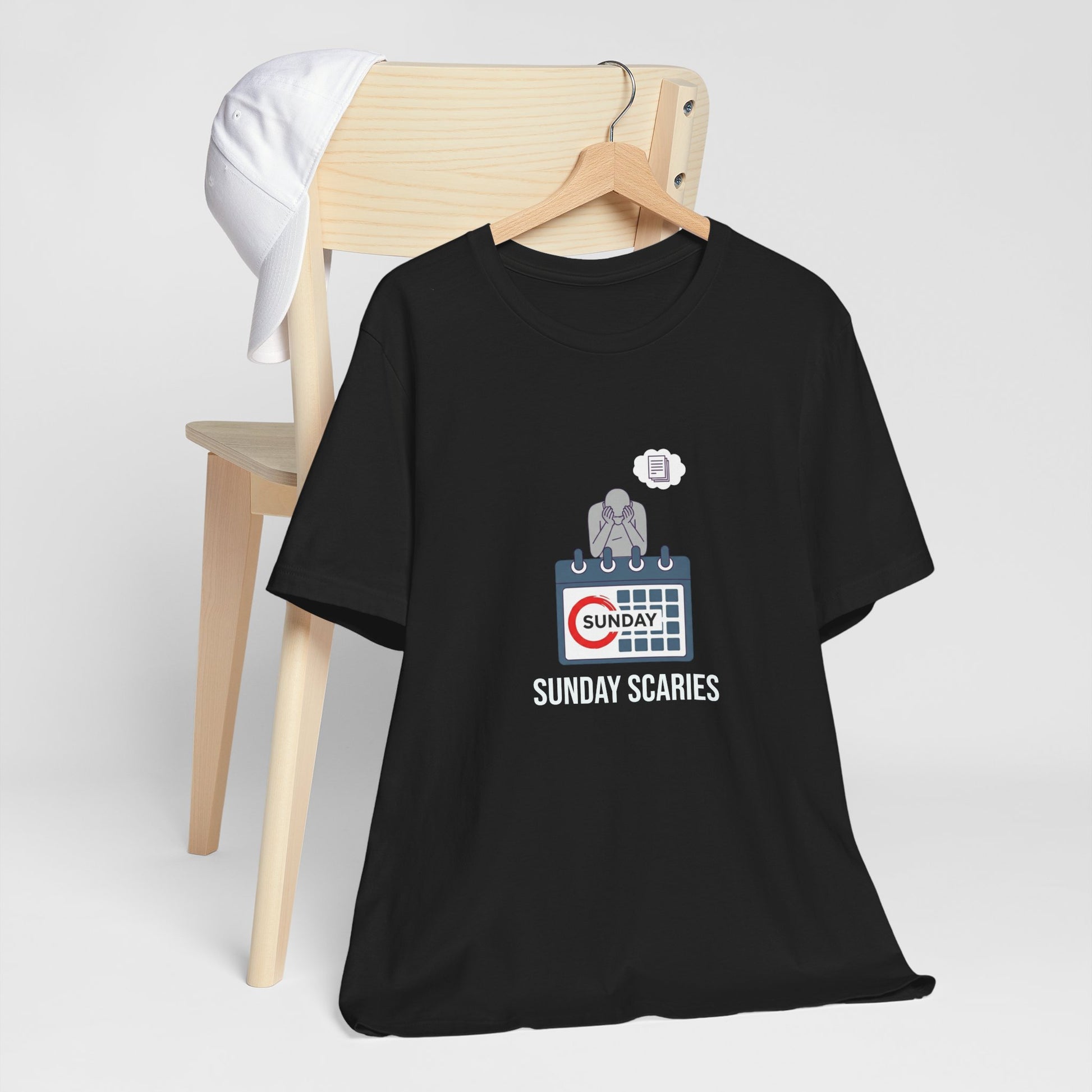 Black t-shirt with 'Sunday Scaries' graphic design on a wooden chair against a white background