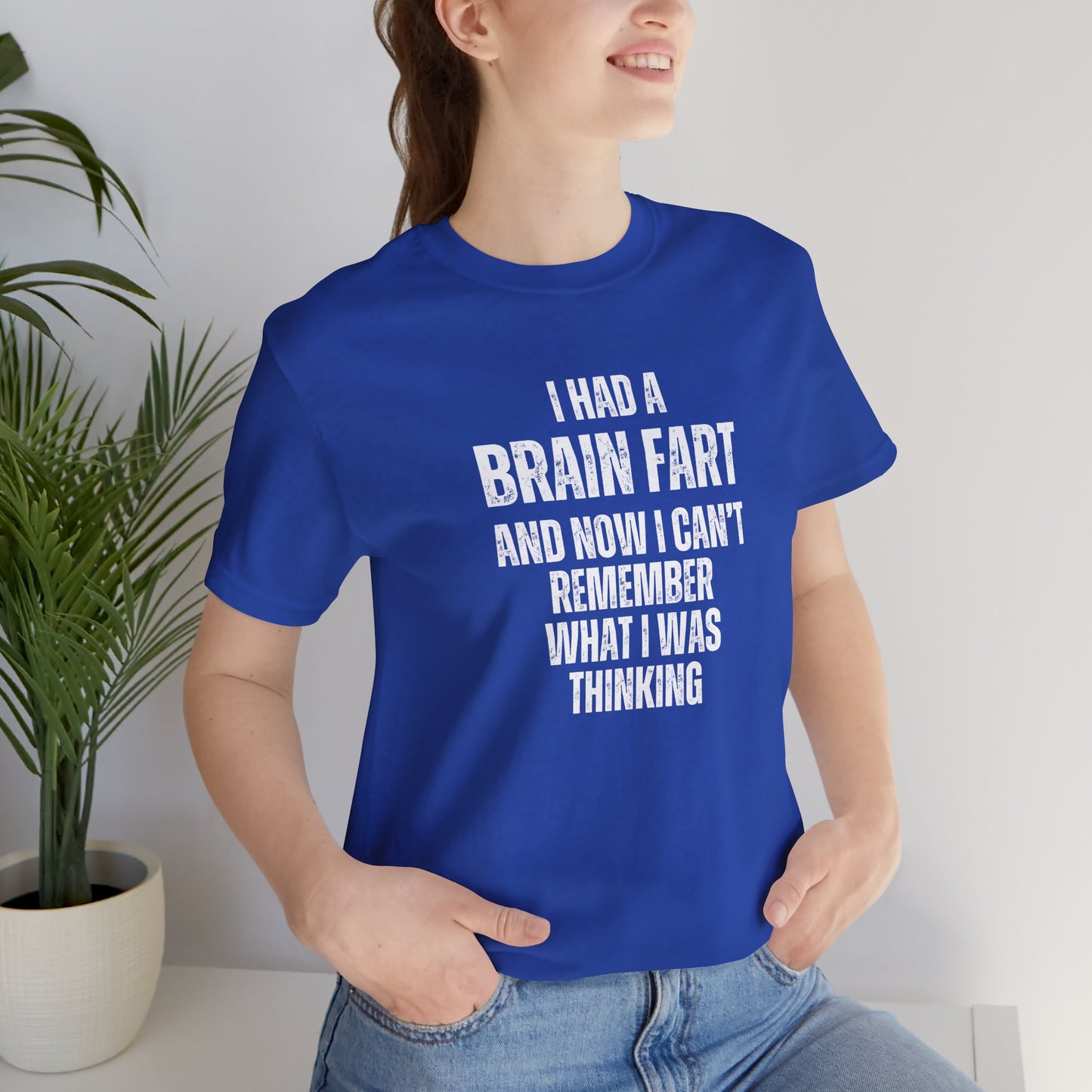 Person wearing a blue t-shirt with humorous text 'I had a brain fart and now I can't remember what I was thinking' in a casual setting