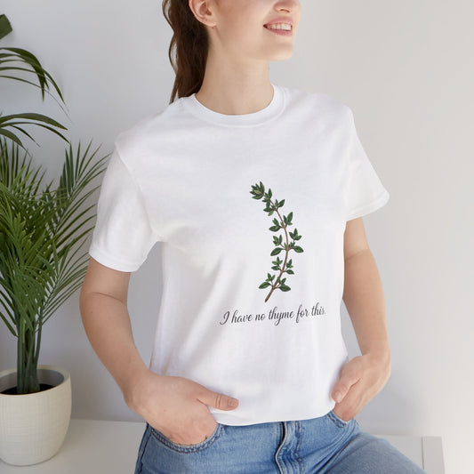 Person wearing a white t-shirt with a plant design and text 'I have no thyme for this', standing next to a potted plant.