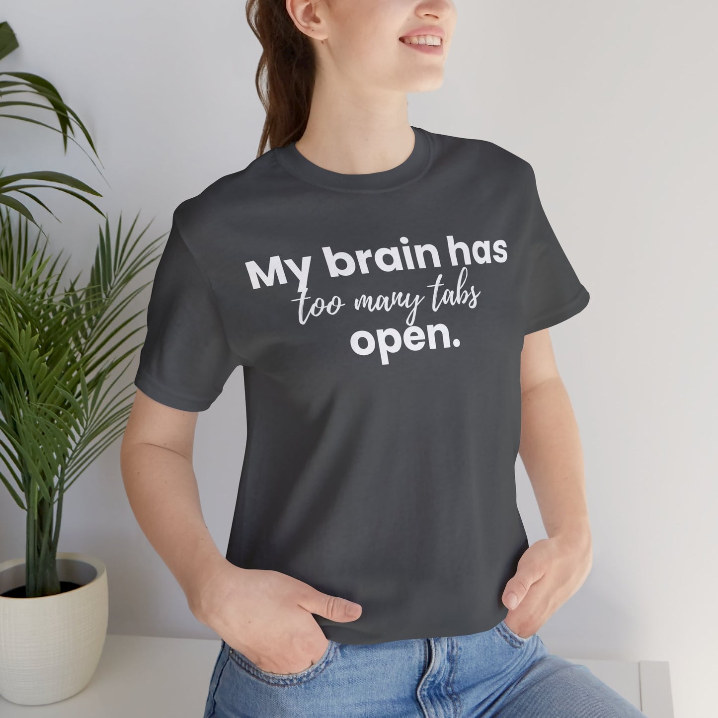 Person wearing a black t-shirt with text 'My brain has too many tabs open' in a casual setting.
