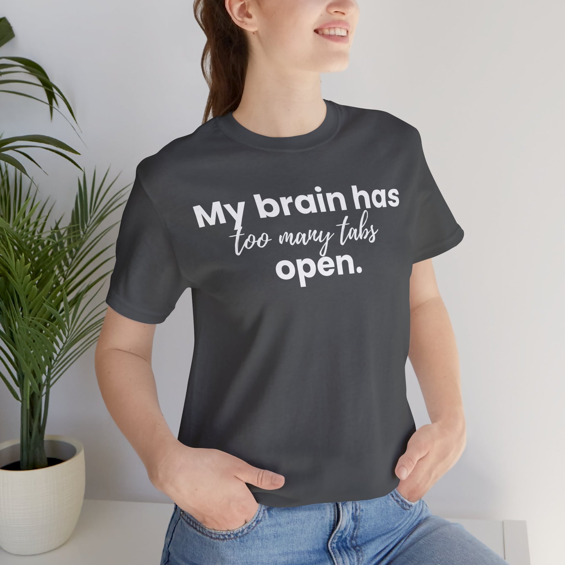 Person wearing a black t-shirt with text 'My brain has too many tabs open' in a casual setting.