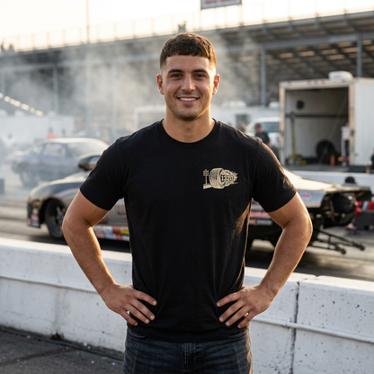 Man standing on a racetrack with cars and smoke in the background