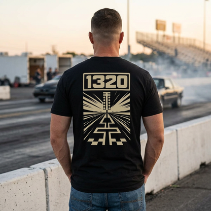 Man wearing a black t-shirt with '1320' design at a race track.