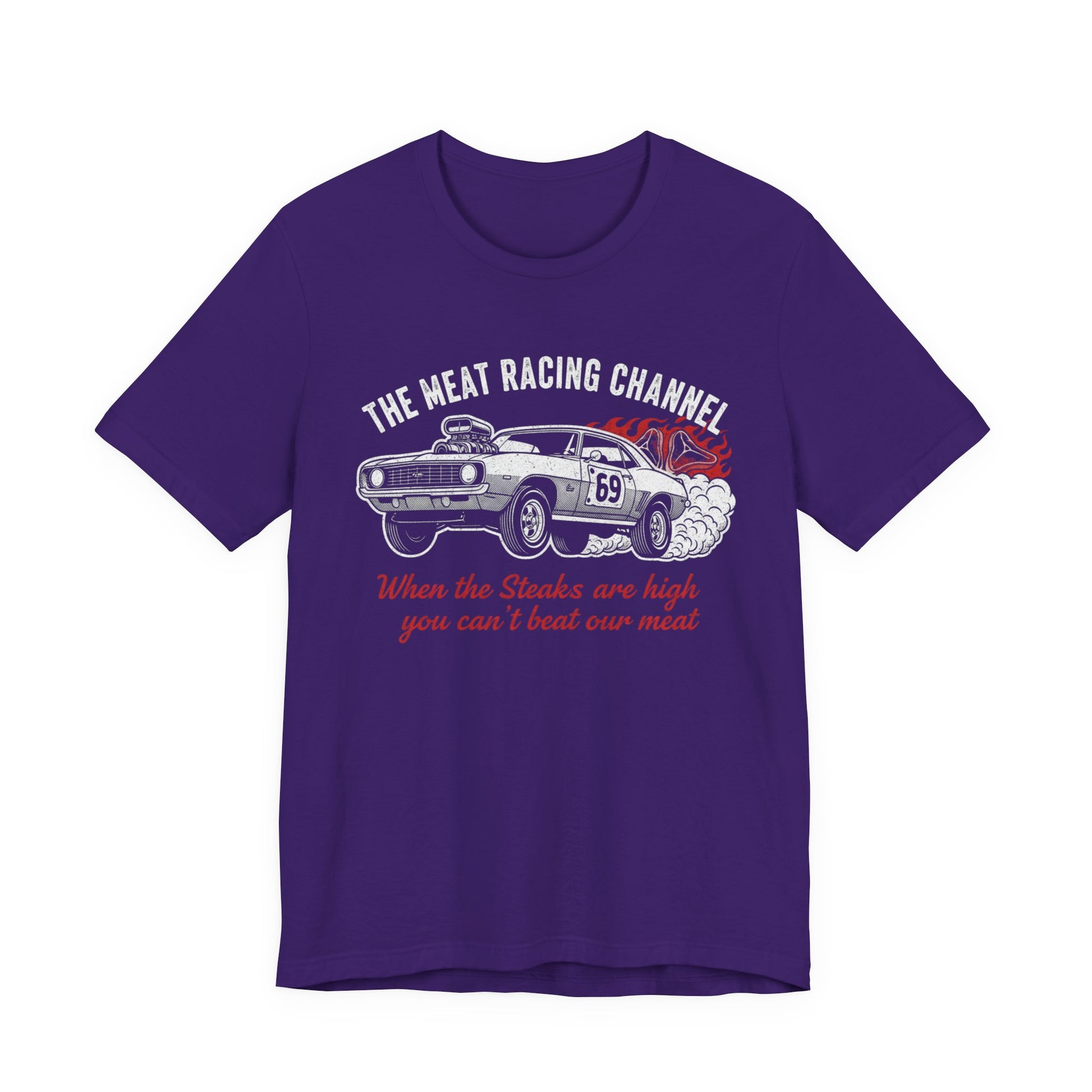 Purple Bella+Canvas 3001 T‑shirt with a bold graphic design. The print features a vintage muscle car with the number 69, white smoke and red flames, the distressed white title “The Meat Racing Channel” above, and the red script tagline “When the Steaks are high you can’t beat our meat” below. Funny drag racing parody shirt with retro hot rod style graphics.
