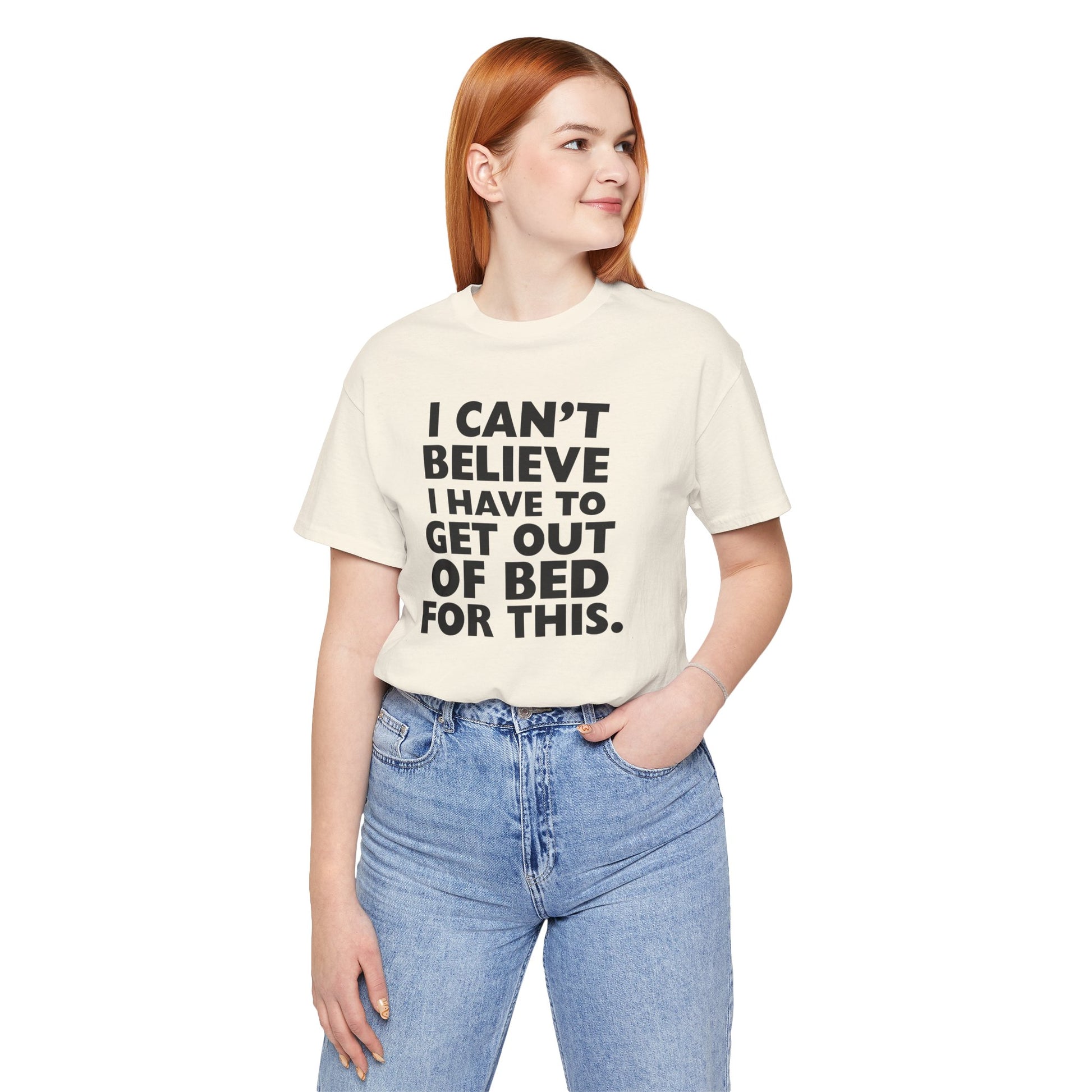 Person wearing a natural t-shirt with black text 'I can't believe I have to get out of bed for this' on a white background