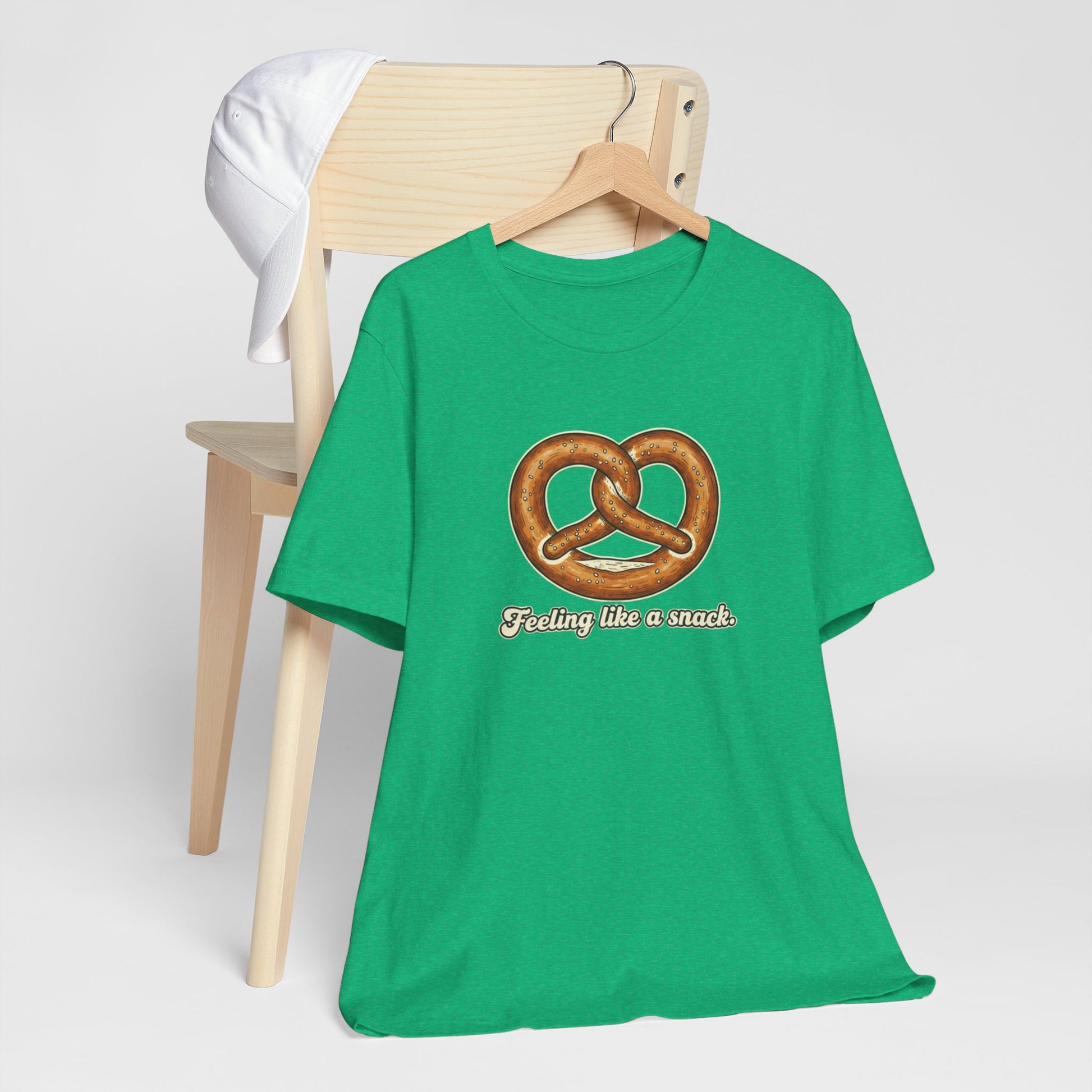 Green t-shirt with pretzel graphic and text 'Feeling like a snack' on a white background