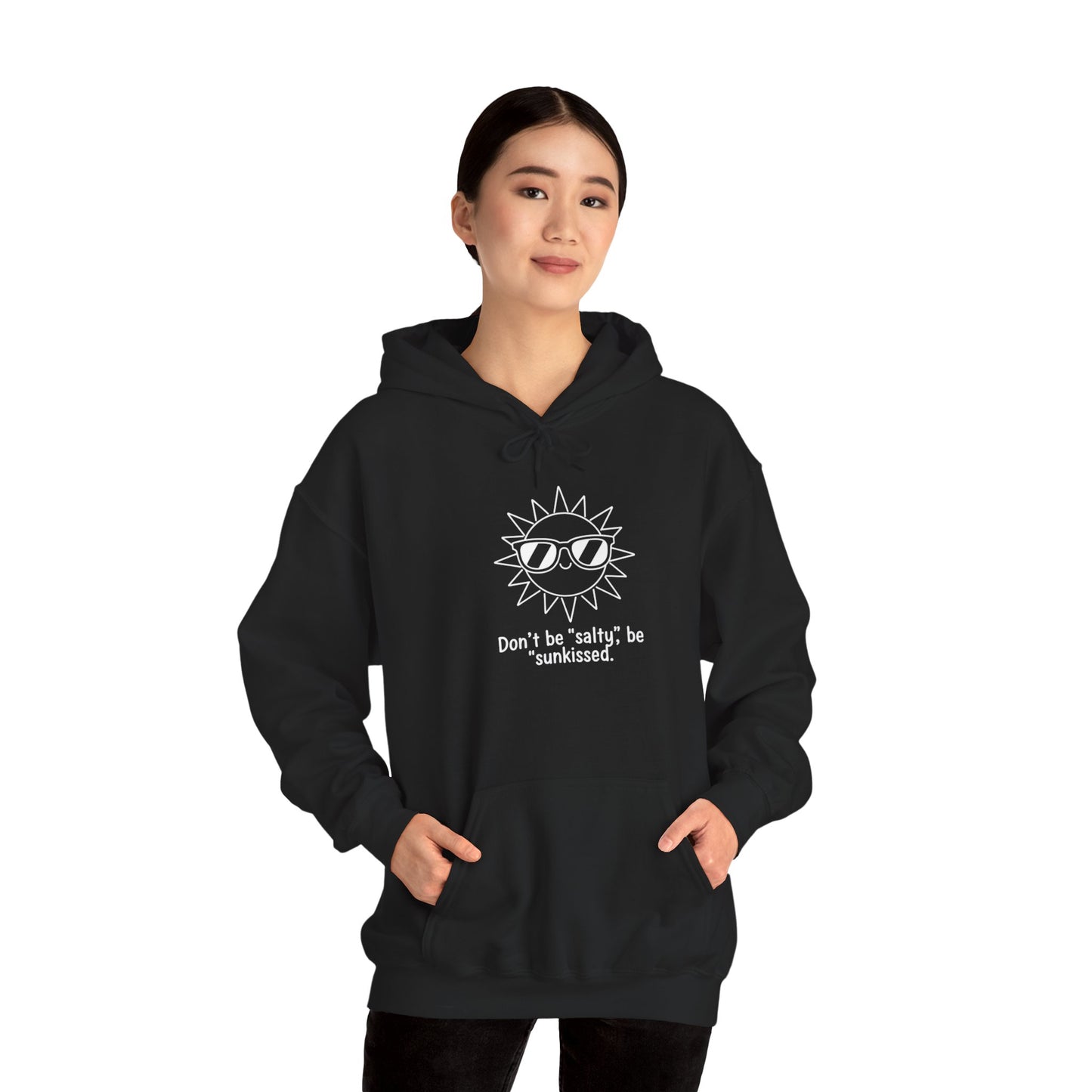 Person wearing a black hoodie with a sun graphic and text 'Don't be salty, be sunkissed' on a white background