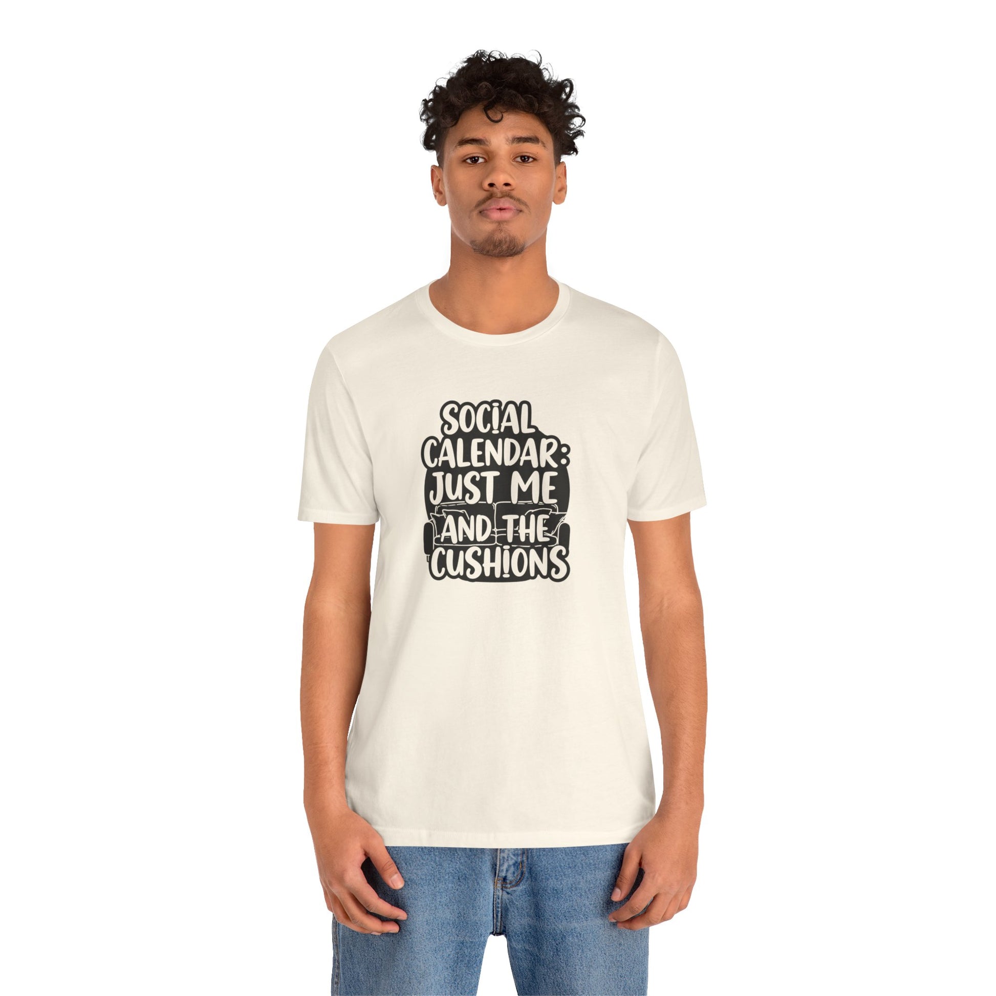 Person wearing a white t-shirt with text 'Social calendar: Just me and the cushions' on a white background