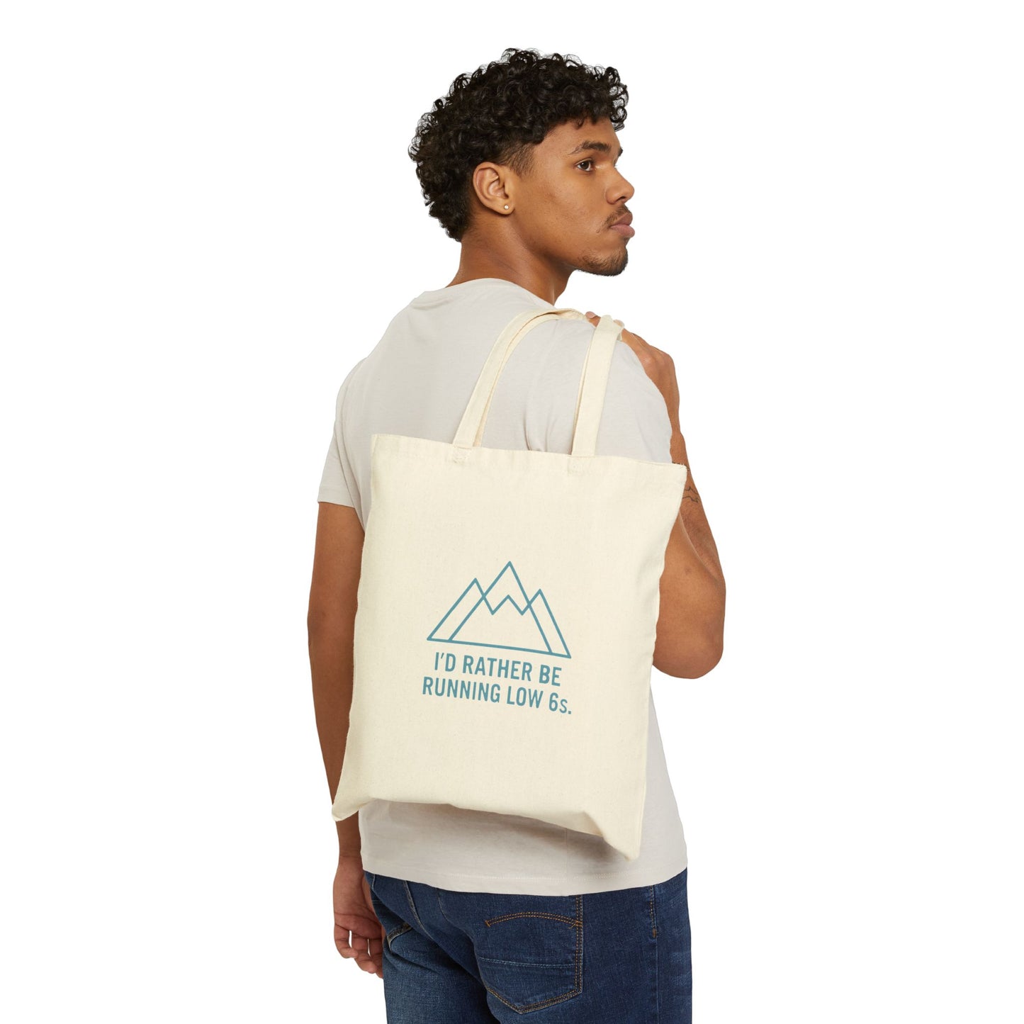 Man carrying a tote bag with a mountain design and text 'I'd rather be running low 6s' on a white background
