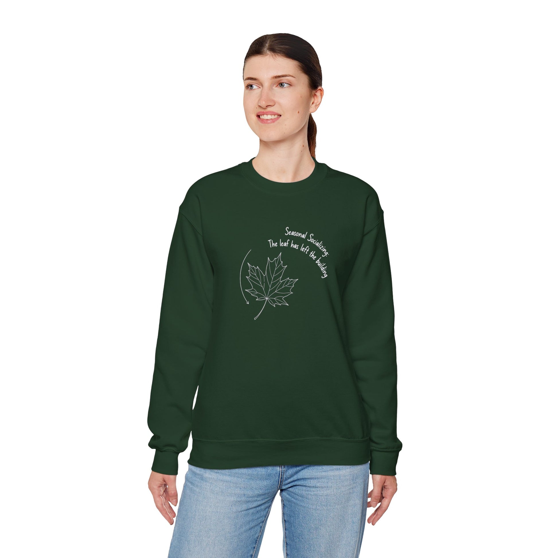 Person wearing a green sweatshirt with a leaf design and text 'Seasonal Socializing, The leaf has left the building' on a white background