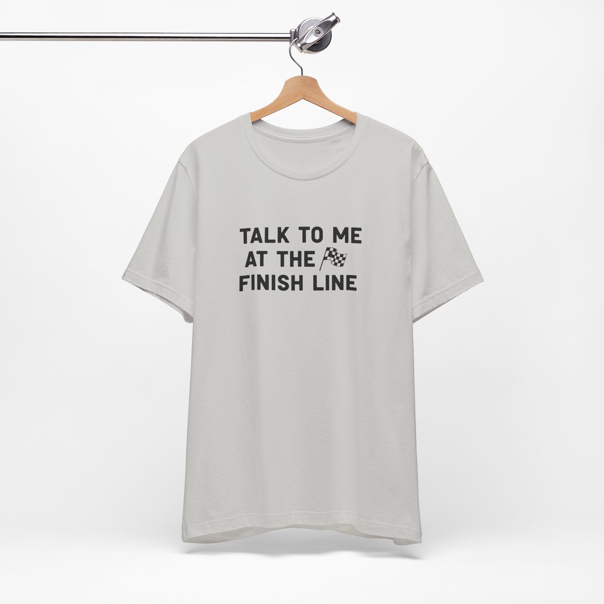 Gray t-shirt with 'Talk to me at the finish line' text on a hanger against a white background