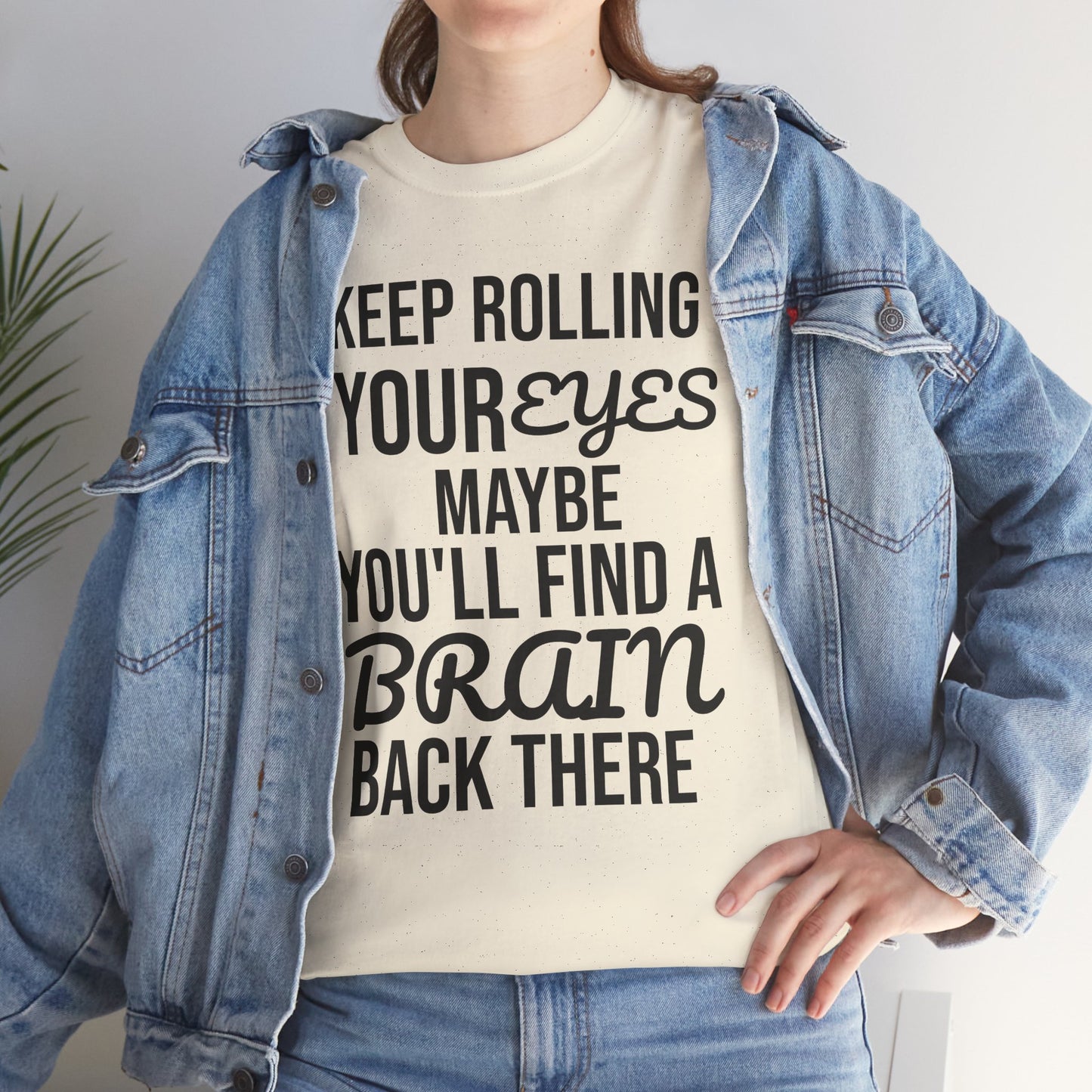 Person wearing a white t-shirt with humorous text 'KEEP ROLLING YOUR EYES MAYBE YOU'LL FIND A BRAIN BACK THERE' and a denim jacket.