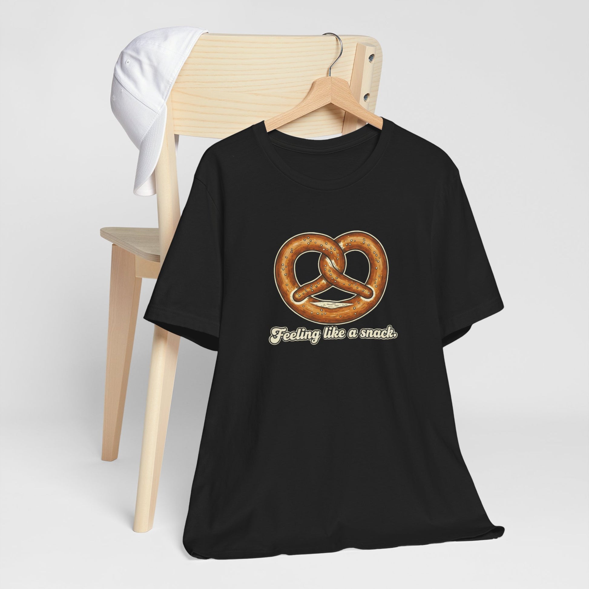 Black t-shirt with pretzel graphic and text 'Feeling like a snack' on a white background