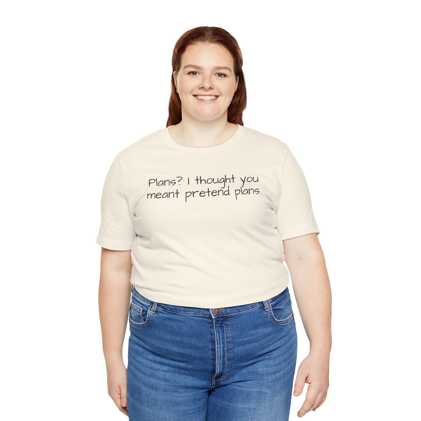 Person wearing a beige t-shirt with text 'Plans? I thought you meant pretend plans' and blue jeans on a white background