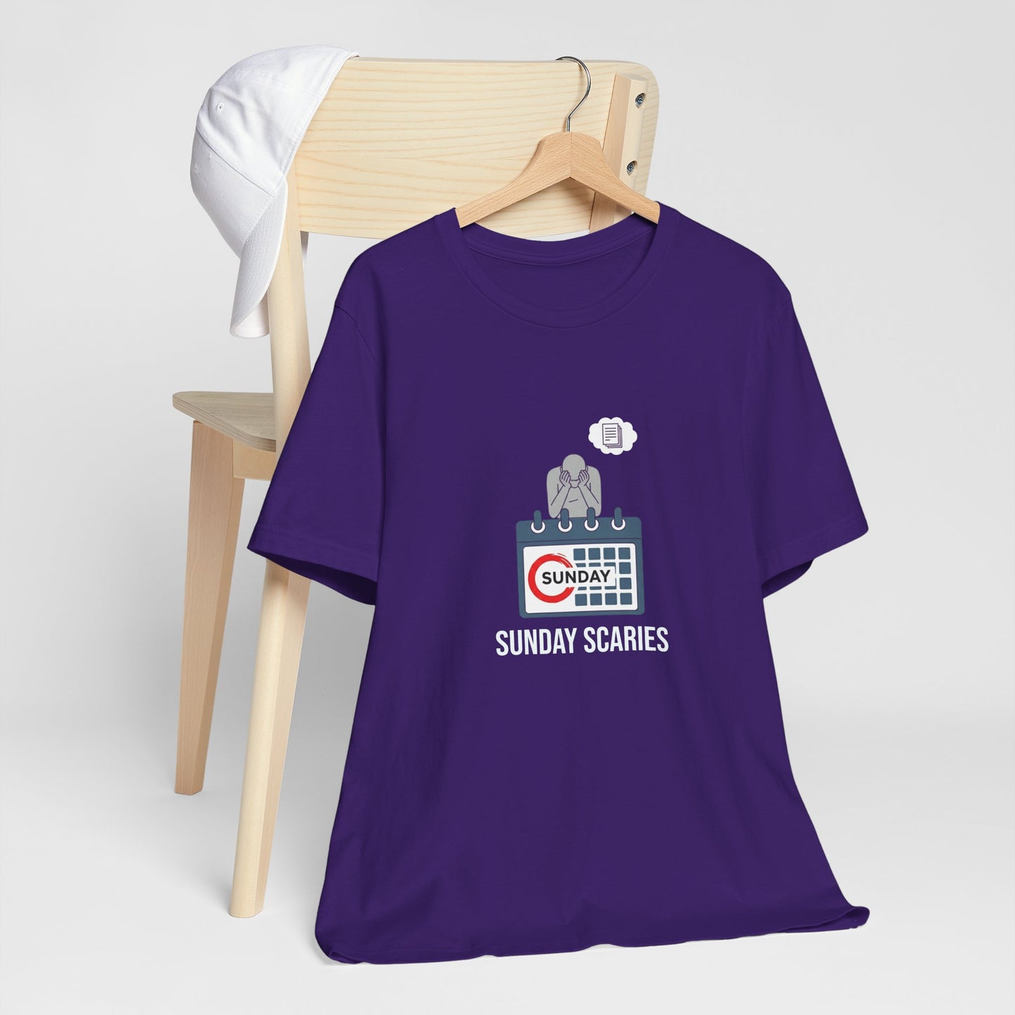 Purple t-shirt with 'Sunday Scaries' graphic on a wooden chair against a white background
