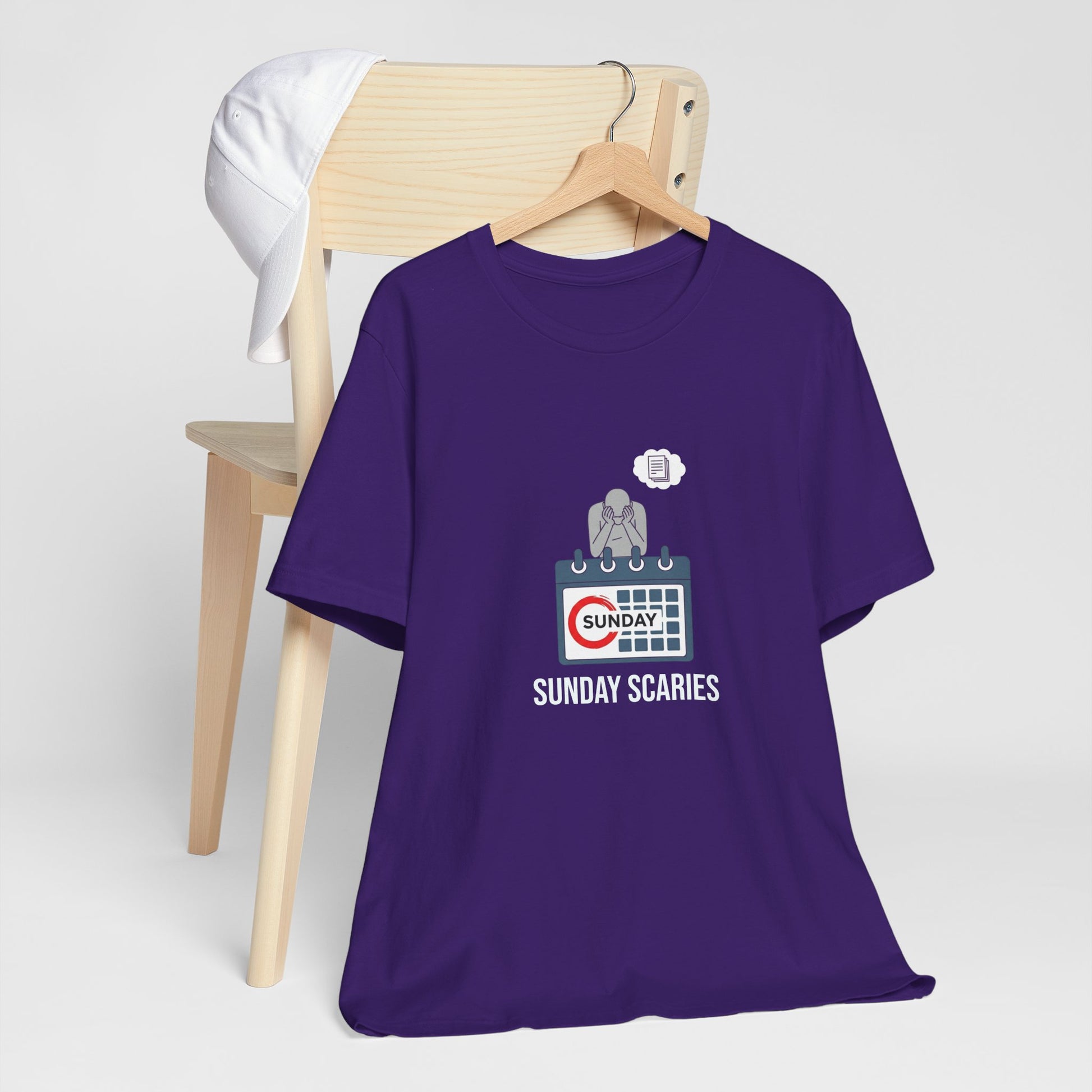 Purple t-shirt with 'Sunday Scaries' graphic on a wooden chair against a white background
