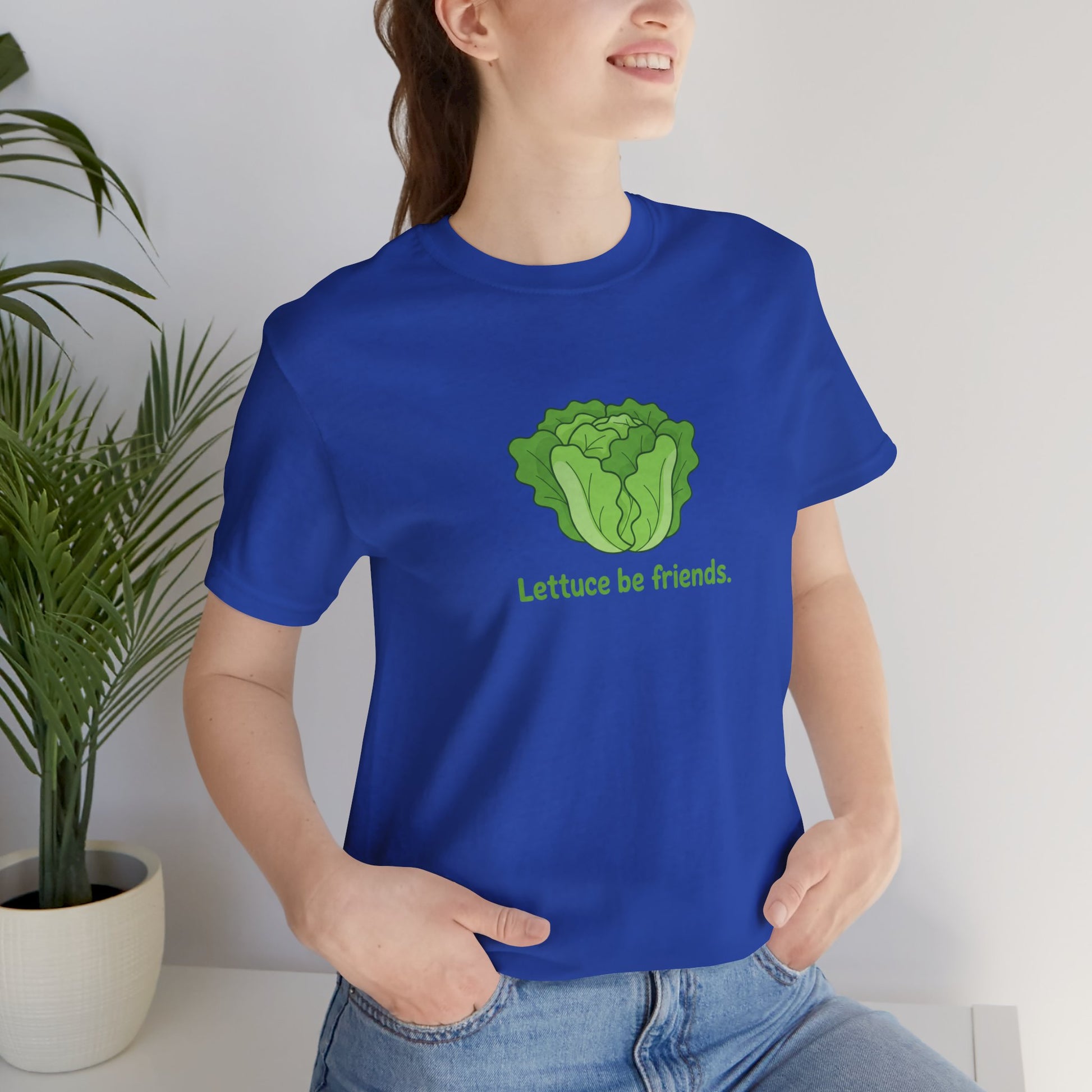 Person wearing a blue t-shirt with a lettuce graphic and text 'Lettuce be friends', standing indoors.