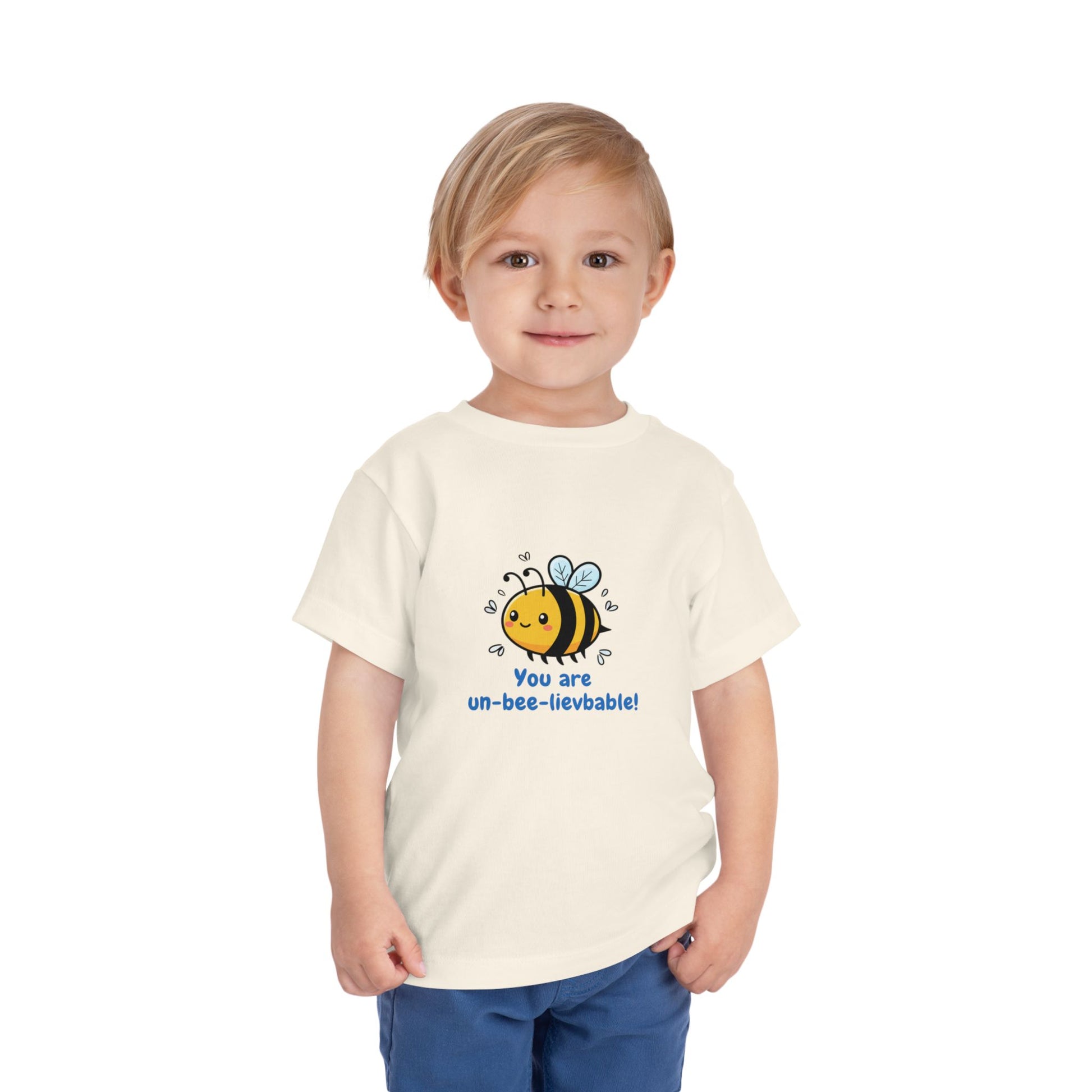 Child wearing a natural 'You Are Un-Bee-Lievable' toddler t-shirt with cute bee graphic – Bella+Canvas 3001T on a white background