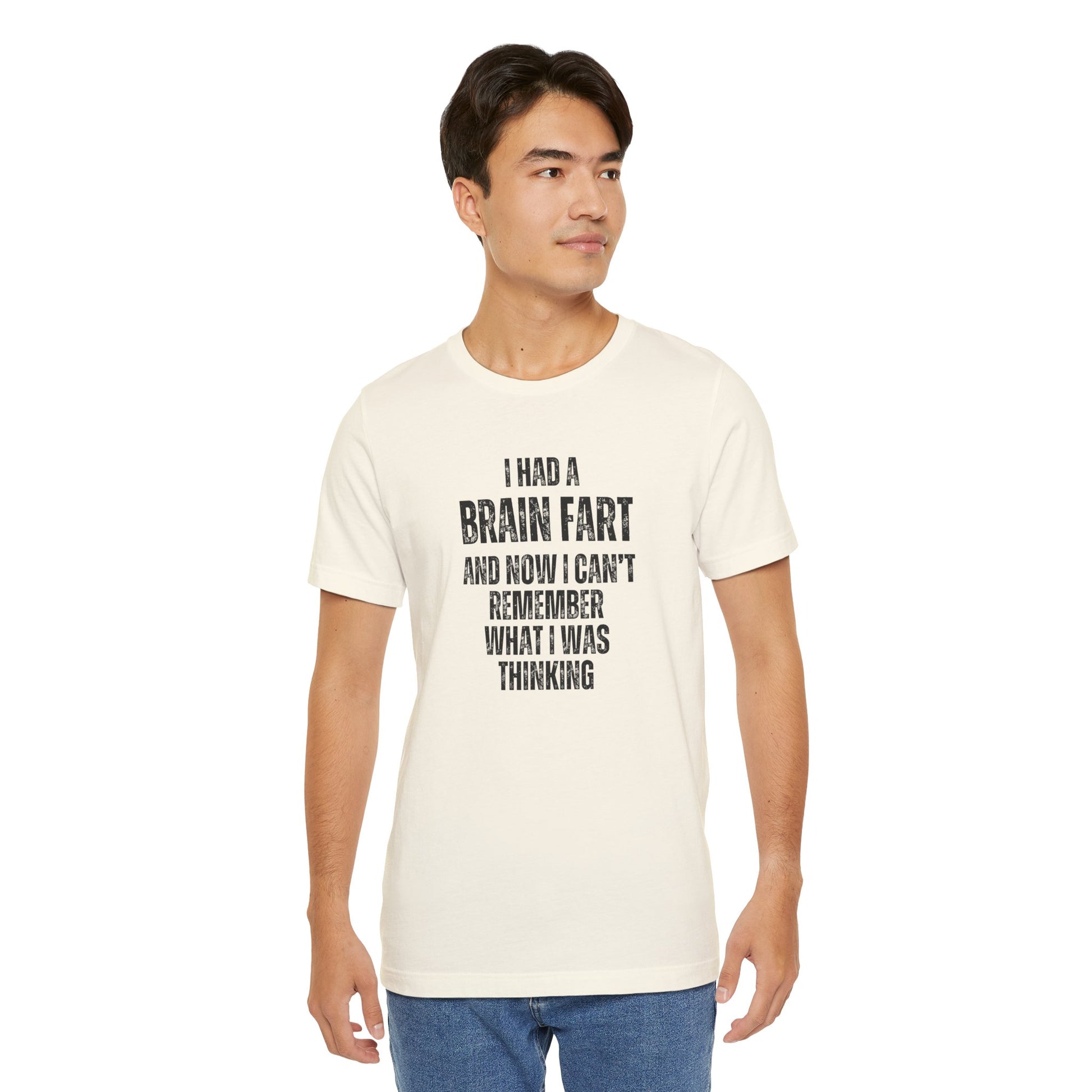 Man wearing a white t-shirt with humorous text 'I had a brain fart and now I can't remember what I was thinking' design on a plain background