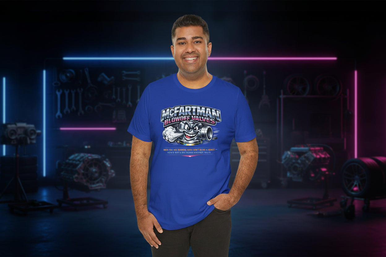 Man wearing a blue t-shirt with a graphic design and 'McFartman Blowoff Valves When You Are Running Hard Don't Blow A Gasket Vent It With A McFartman Blowout Valve' text in a dark, neon-lit room.