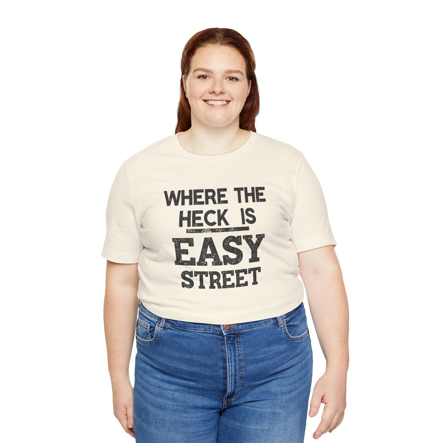 Person wearing a beige t-shirt with text 'Where the heck is Easy Street' and blue jeans on a white background