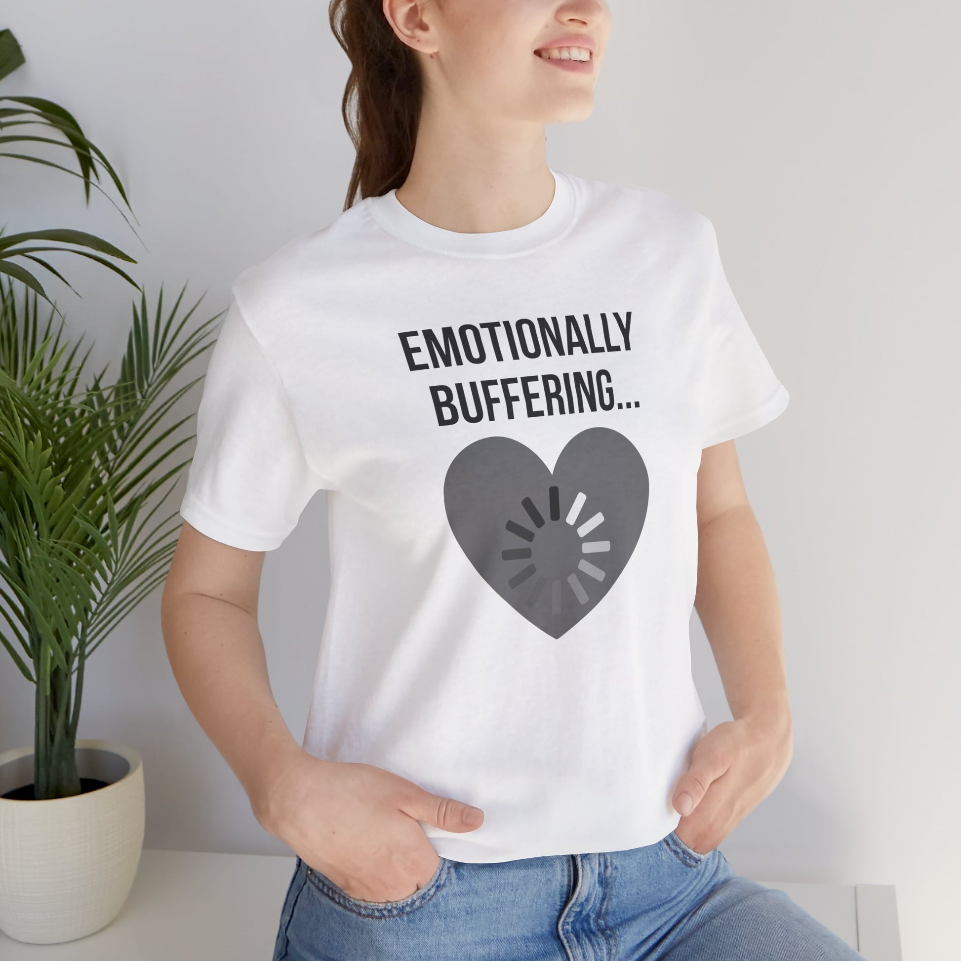 Person wearing a white t-shirt with 'Emotionally Buffering...' text and heart design.