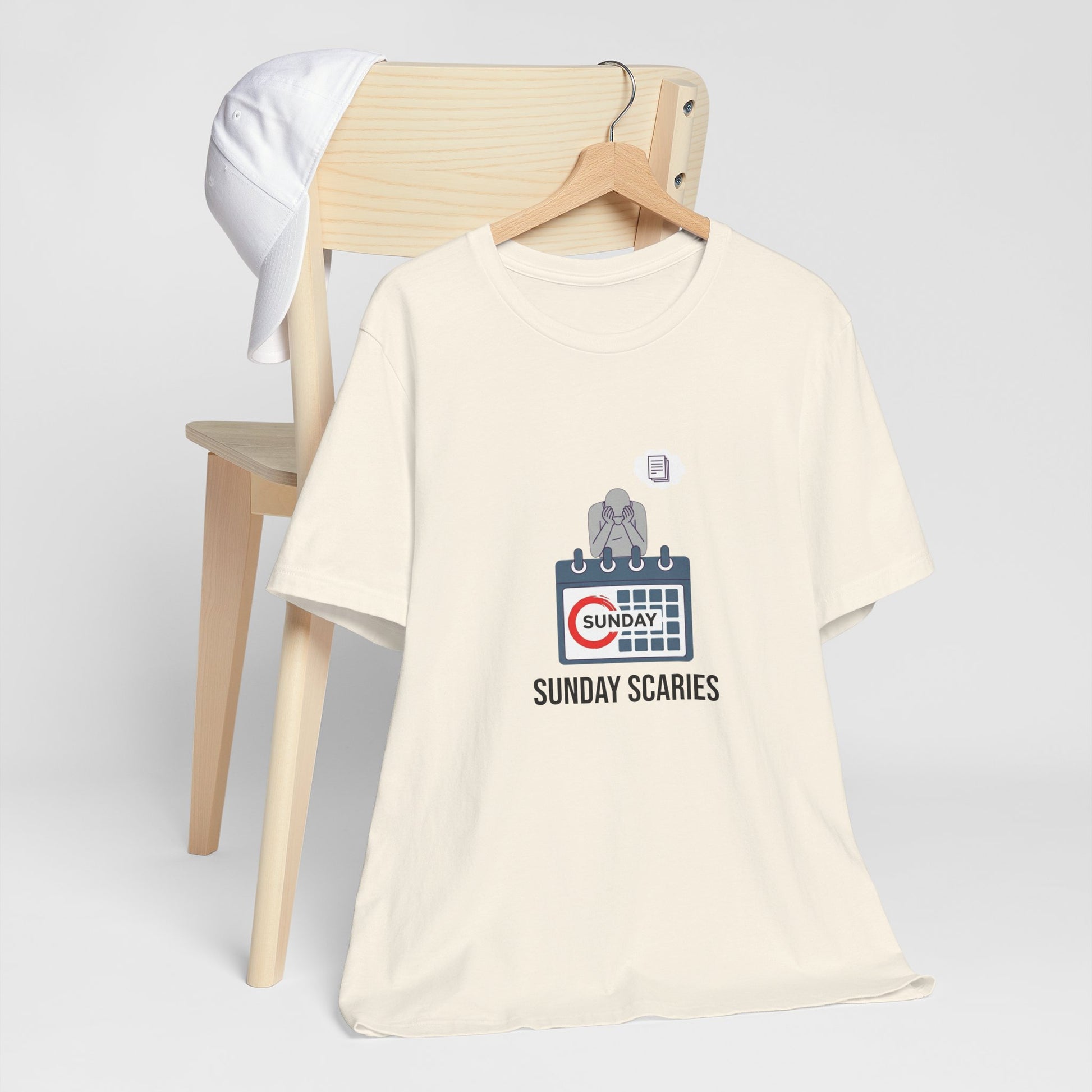 Beige t-shirt with graphic design and text 'Sunday Scaries' on a chair against a white background