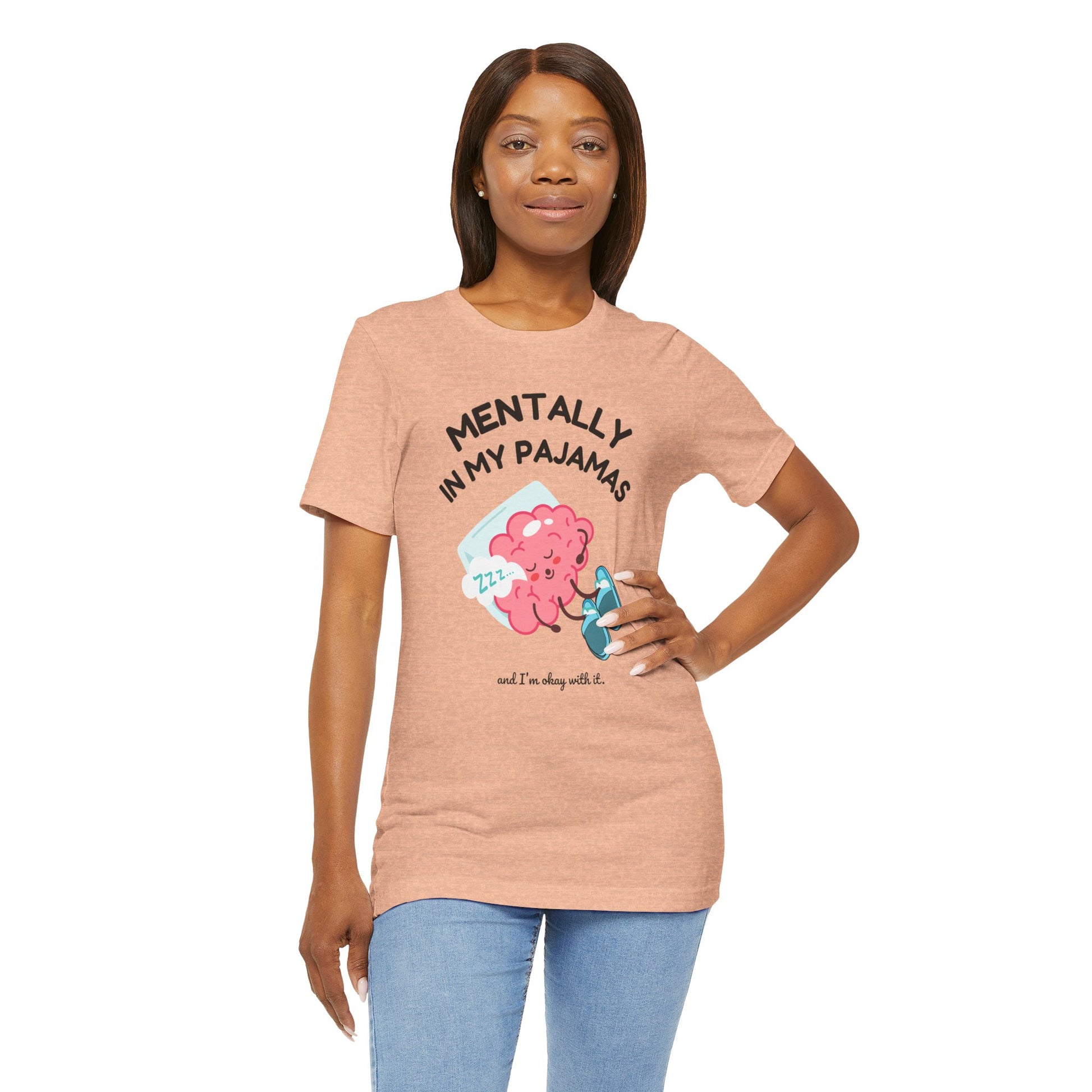Woman wearing a peach t-shirt with a graphic and text 'Mentally in my pajamas and I'm ok with it' on a white background