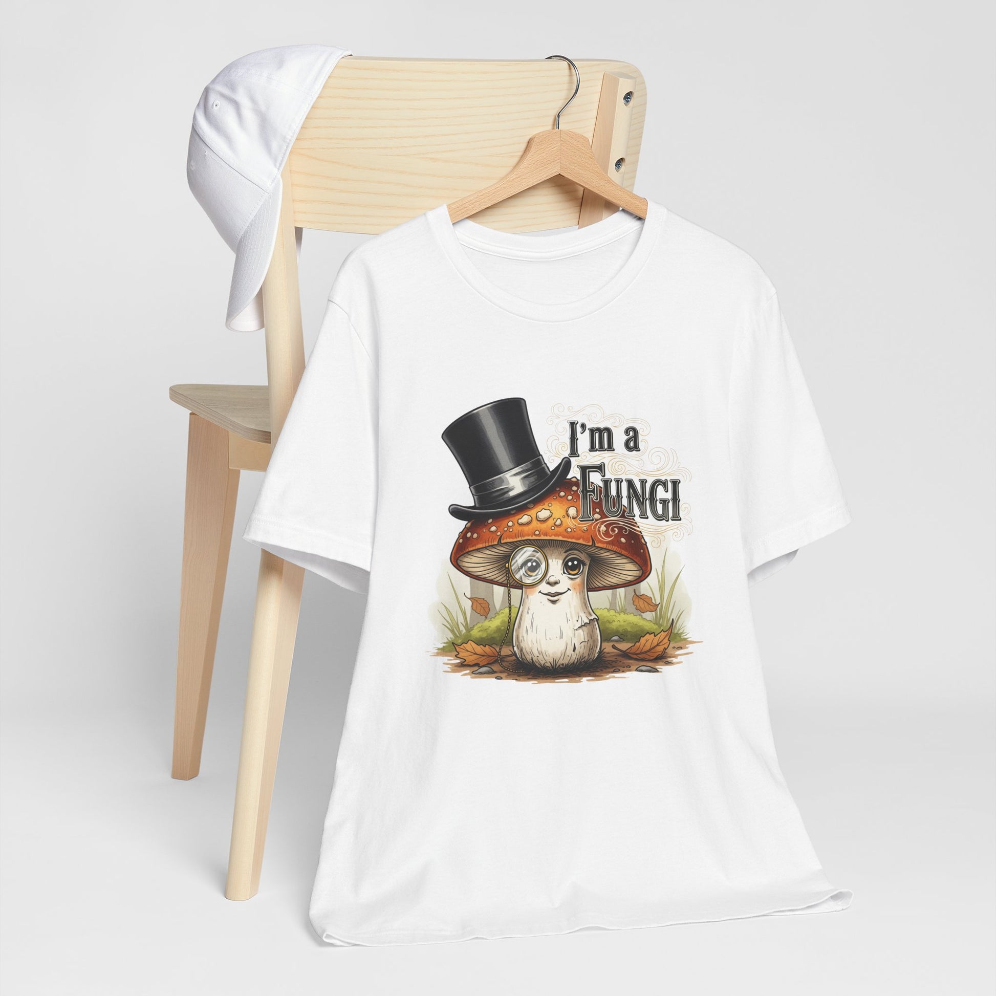 White t-shirt with a graphic design of a mushroom and text 'I'm a Fungi' on a wooden chair.